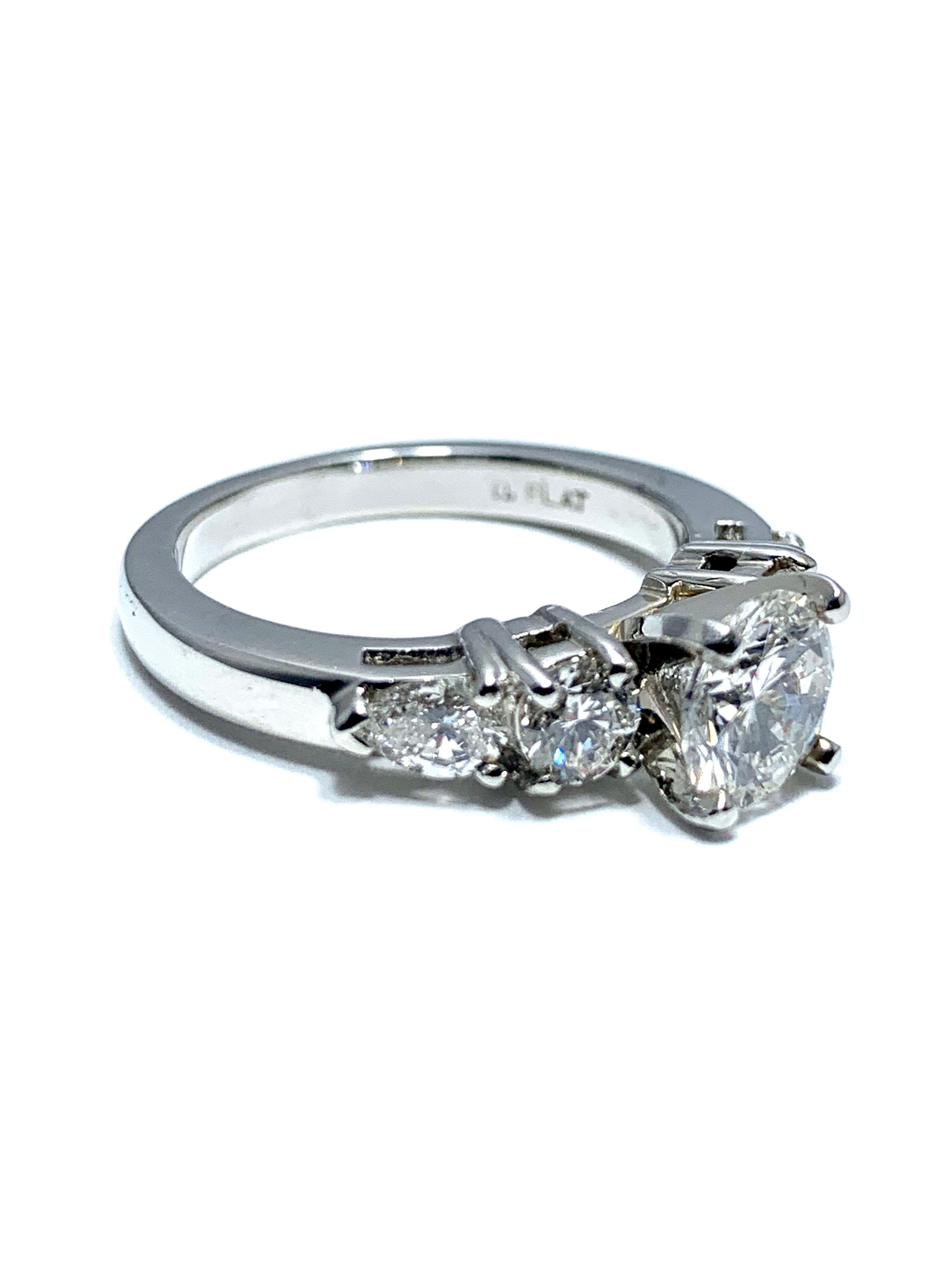 An eye catching 1.05 carat round brilliant cut diamond engagement ring.  The center diamond is set in a four prong platinum head, set with two round and two pear shape diamonds on each side of the platinum shank.  The four side diamonds have a total