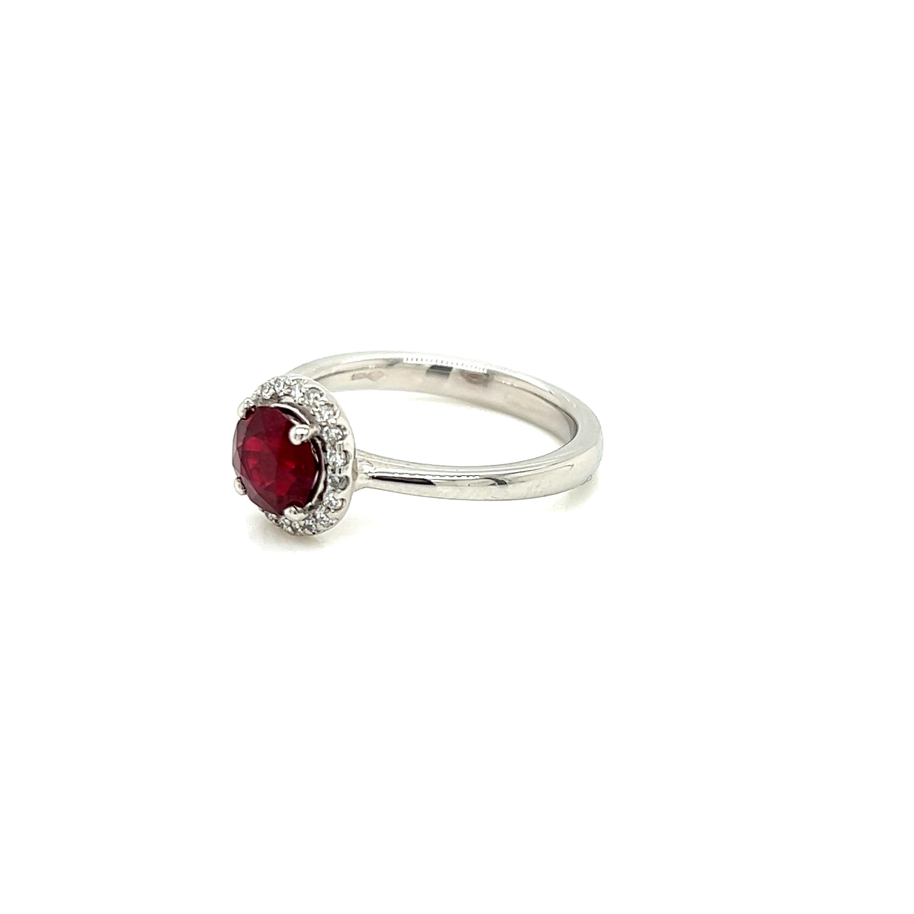 This opulent Platinum ring features a regal 1.05 carat round brilliant Ruby at its centre. Surrounding it is a halo of iridescent Diamonds weighing 0.12 carats.

The Ruby is a brilliant, deep, vivid red. Its rich tones are brought out by the