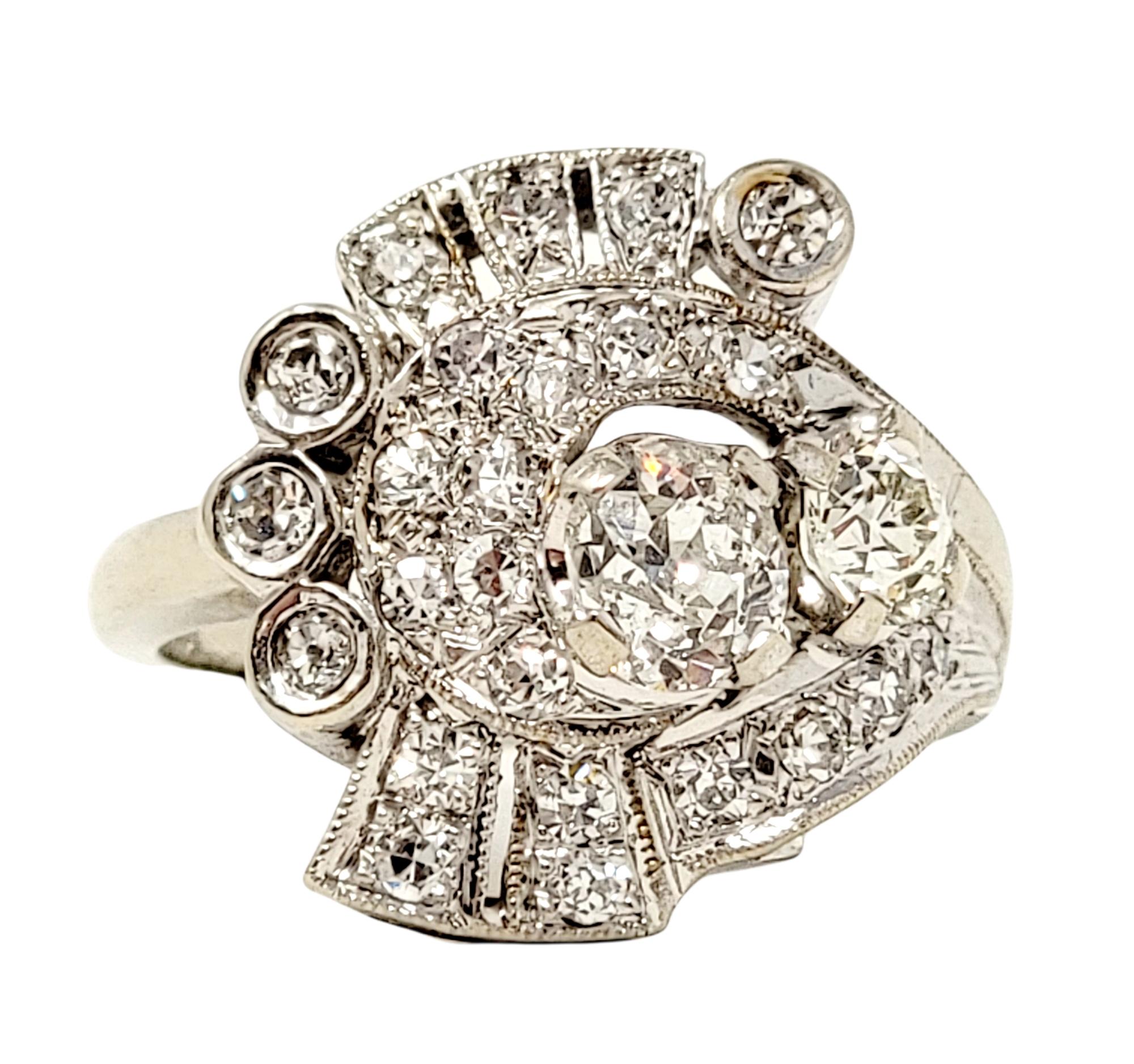 Ring size: 5.25

Beautiful vintage diamond ring arranged in a unique artful design.  It features 26 Old Mine cut diamonds (I-J/ I1) bezel, prong and bead set in a variety of shapes and sizes in an asymmetric swirl-like pattern. The diamonds are set