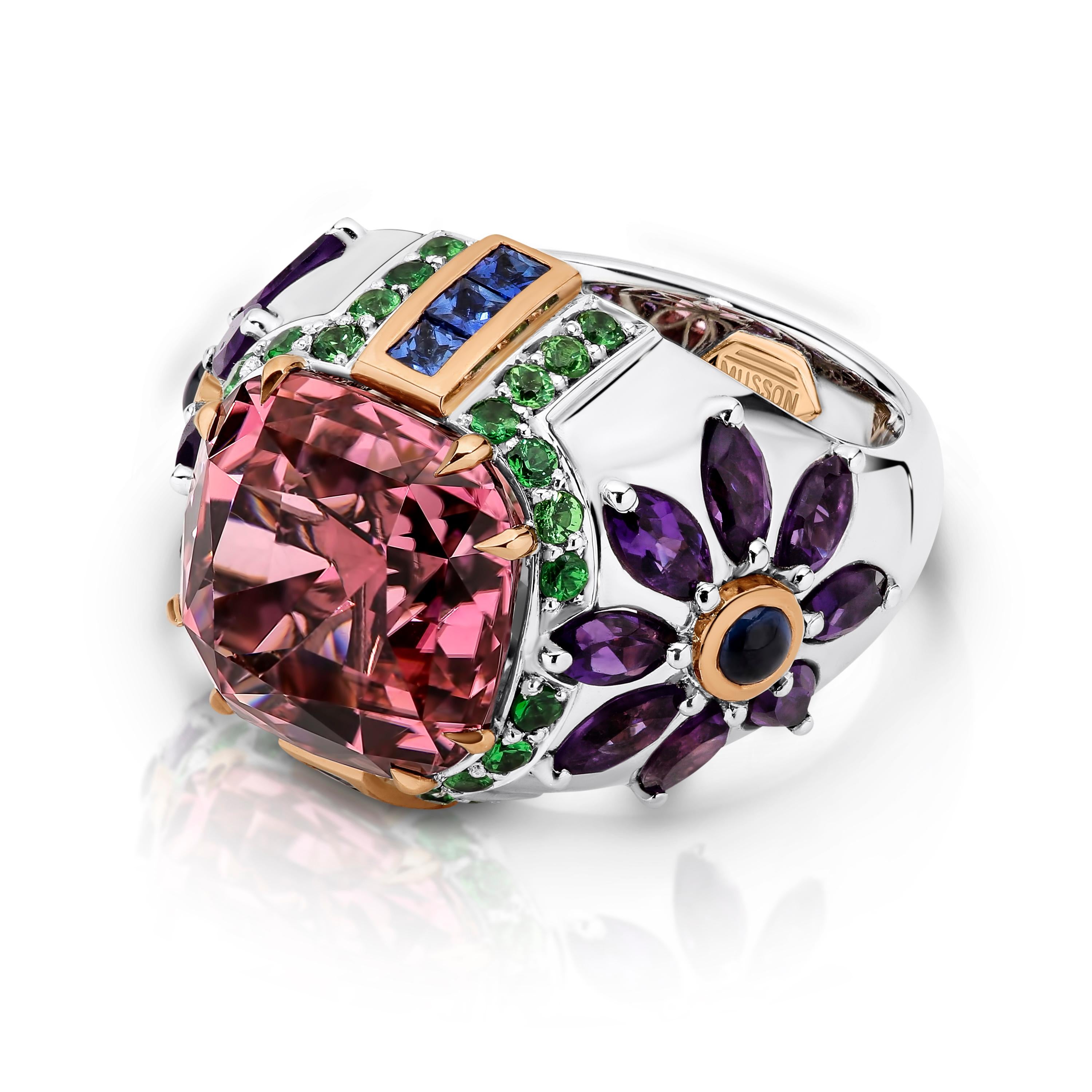 18ct white and rose gold Tourmaline, Garnet, Sapphire, Amethyst 'Poppy' ring designed and produced by Musson. Reference: R35313. The ring is a white gold, tapered domed style and features a large central cushion cut pink tourmaline double claw set