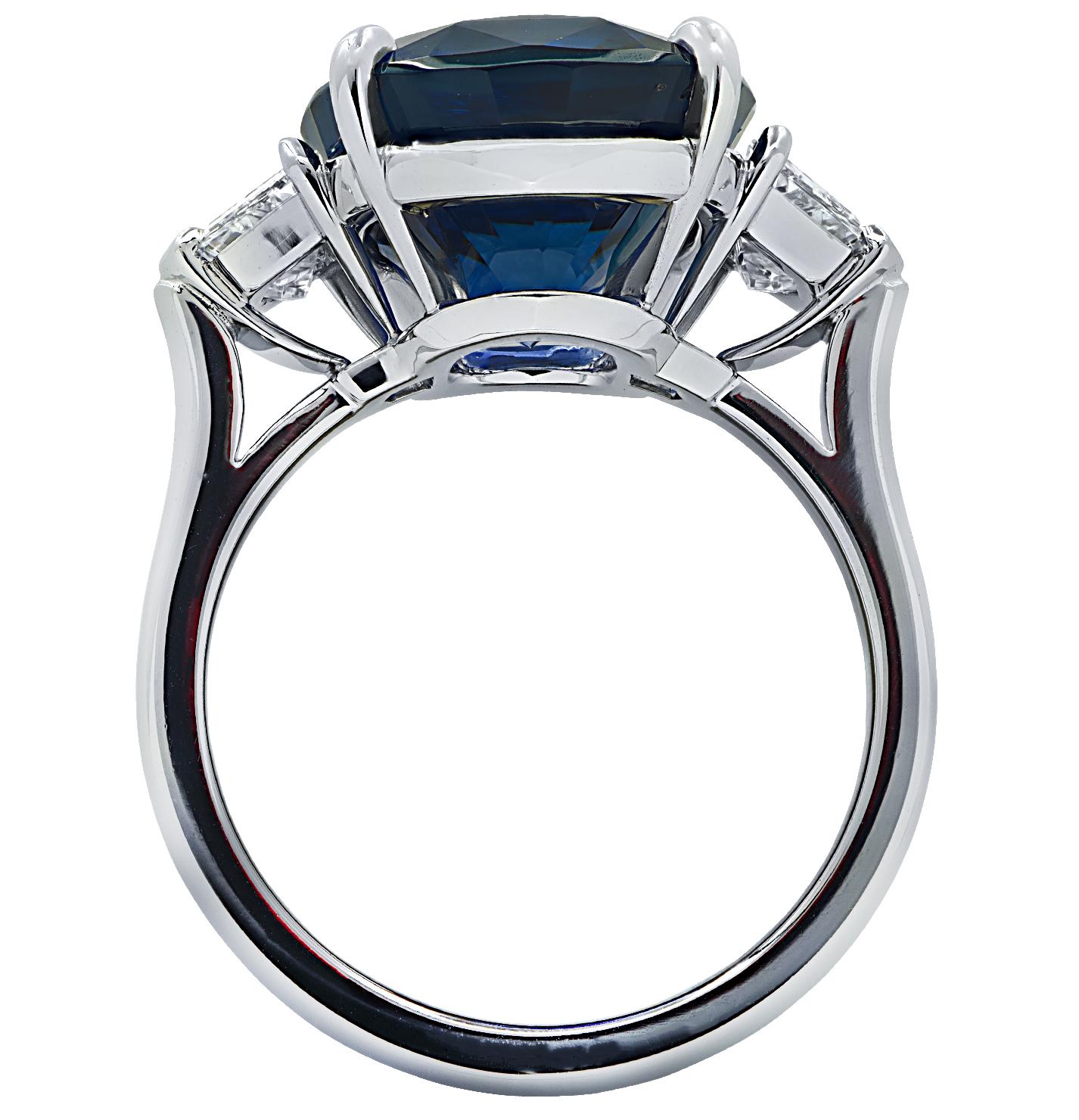Exquisite ring crafted in platinum showcasing a spectacular cushion cut blue Sapphire weighing 10.56 carats, accompanied by two Cadillac cut diamonds weighing 1.02 carats total, E color VS clarity. The face of this sensational ring measures 13.7 mm