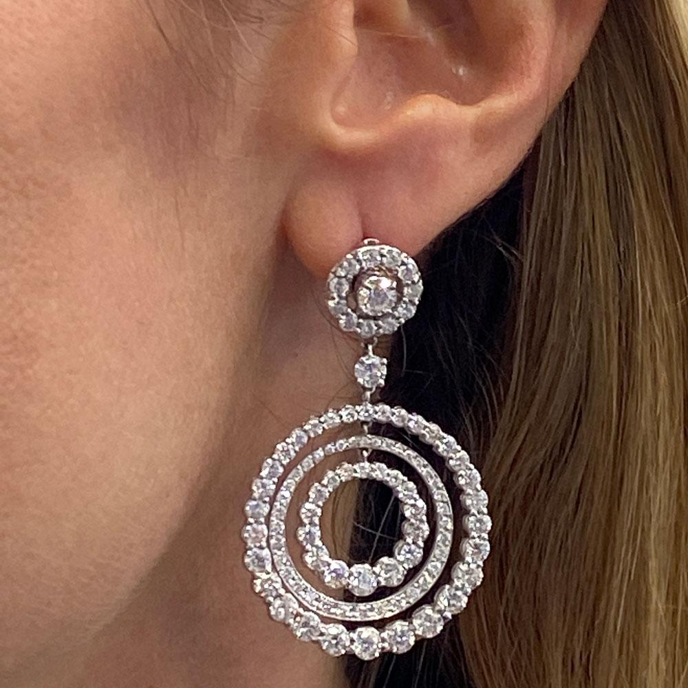 Stunning diamond multi circle drop earrings crafted in 18 karat white gold. The three circle drops feature varying sizes of colorless round brilliant cut diamonds. In all, the earrings are set with 10.58 carats of diamonds graded F-G color and VS