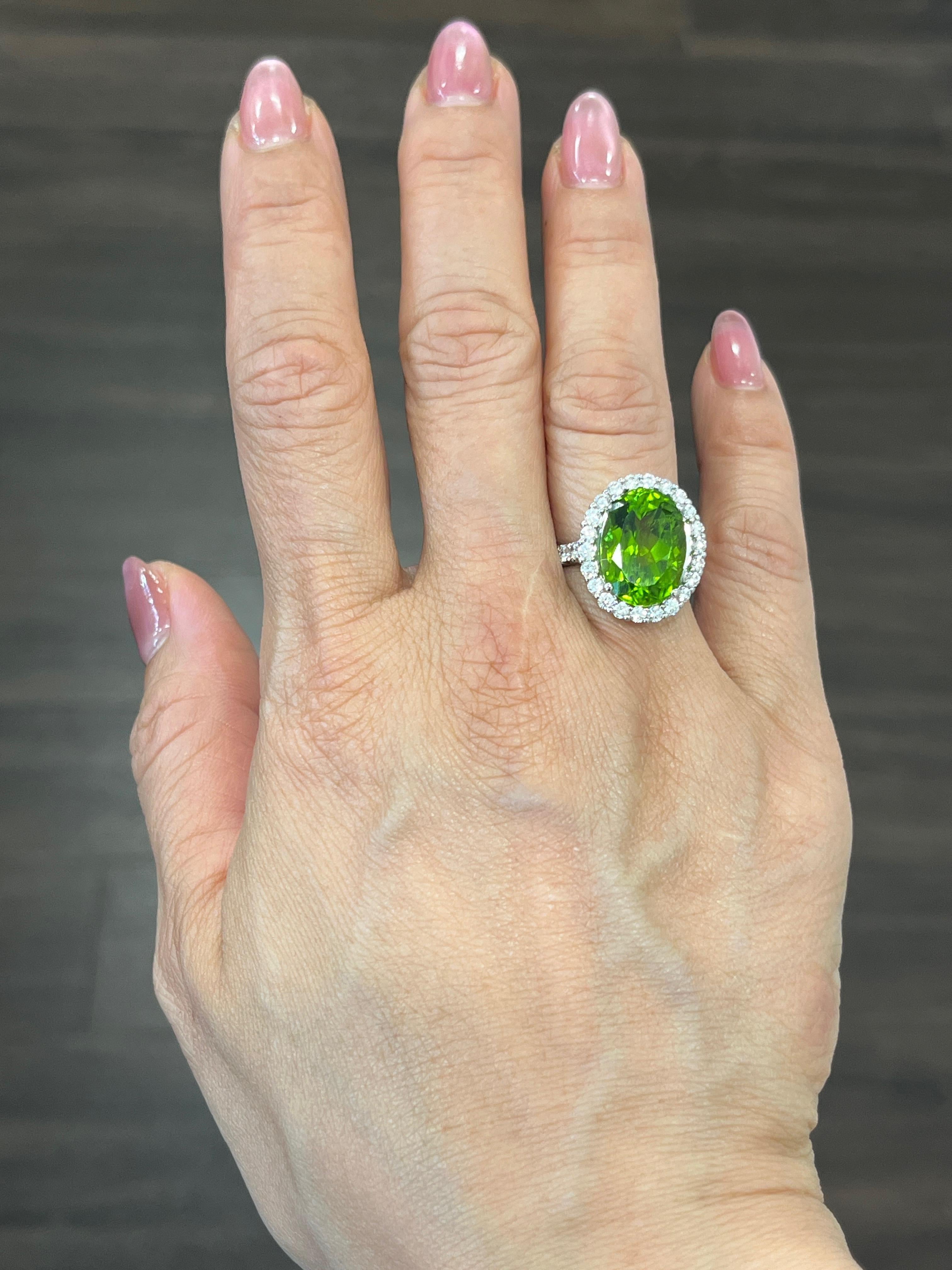 This stunning 18k white gold ring is set with a natural green peridot that weighs 9.35 ct. It is surrounded with 28 round cut diamonds weighing 1.24 ct. The ring boasts a color of F/G and a clarity of VS1. Such an amazing ring, it is sure to turn