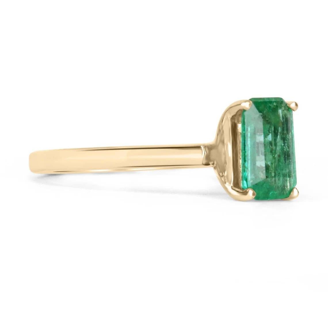 Displayed is a classic emerald solitaire emerald-cut engagement ring/right-hand ring in 14K yellow gold. This gorgeous solitaire ring carries a full 1.05-carat emerald in a four-prong setting. Fully faceted, this gemstone showcases excellent shine.