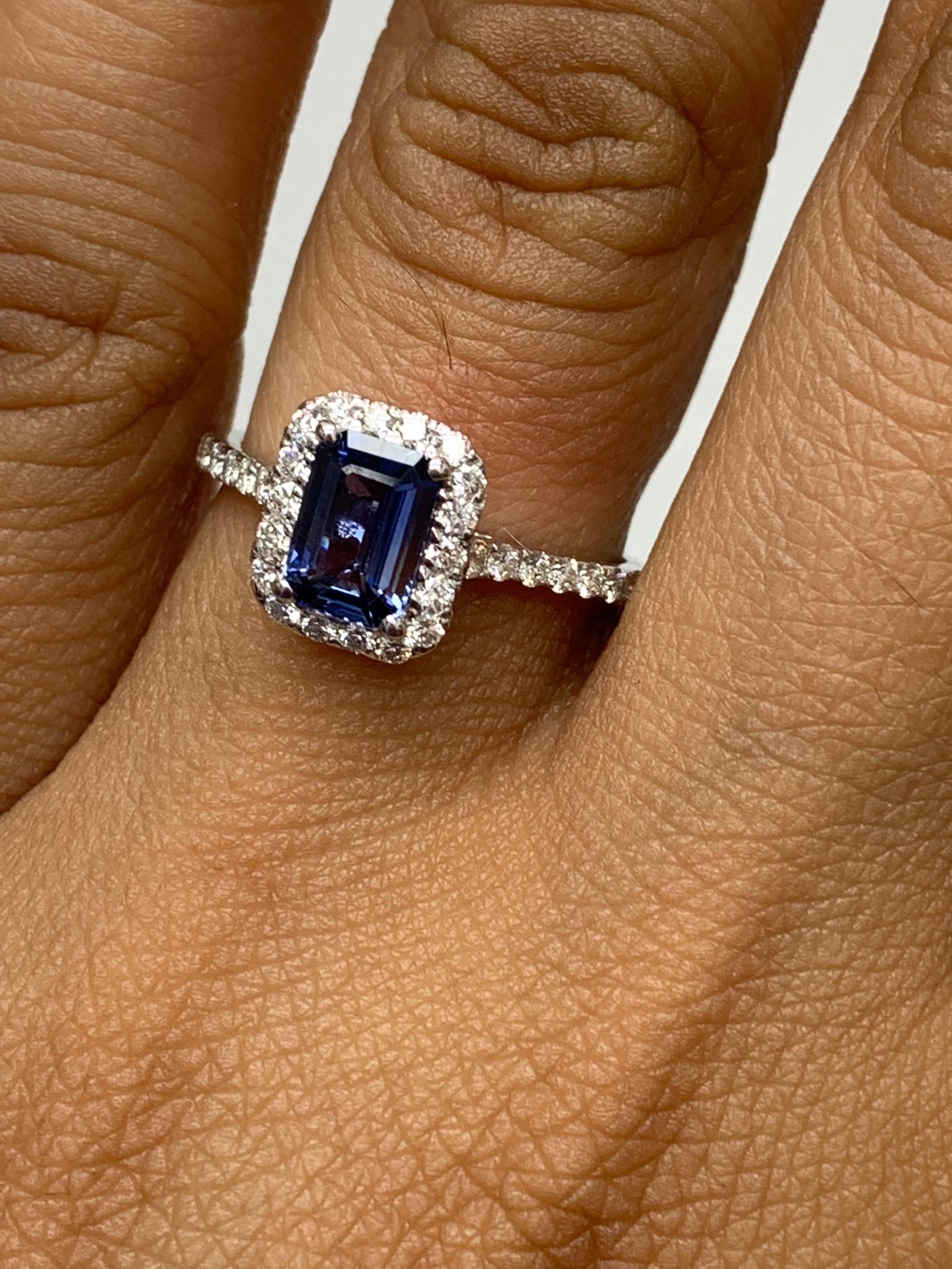 Zeigt einen blauen Saphir im Smaragdschliff mit einem Gewicht von 1,06 Karat, umgeben von einer einzigen Reihe von 36 runden Brillanten in einem nahtlosen Halo-Design. Eingefasst in ein dünnes Band aus 14 Karat Weißgold, das mit Diamanten besetzt