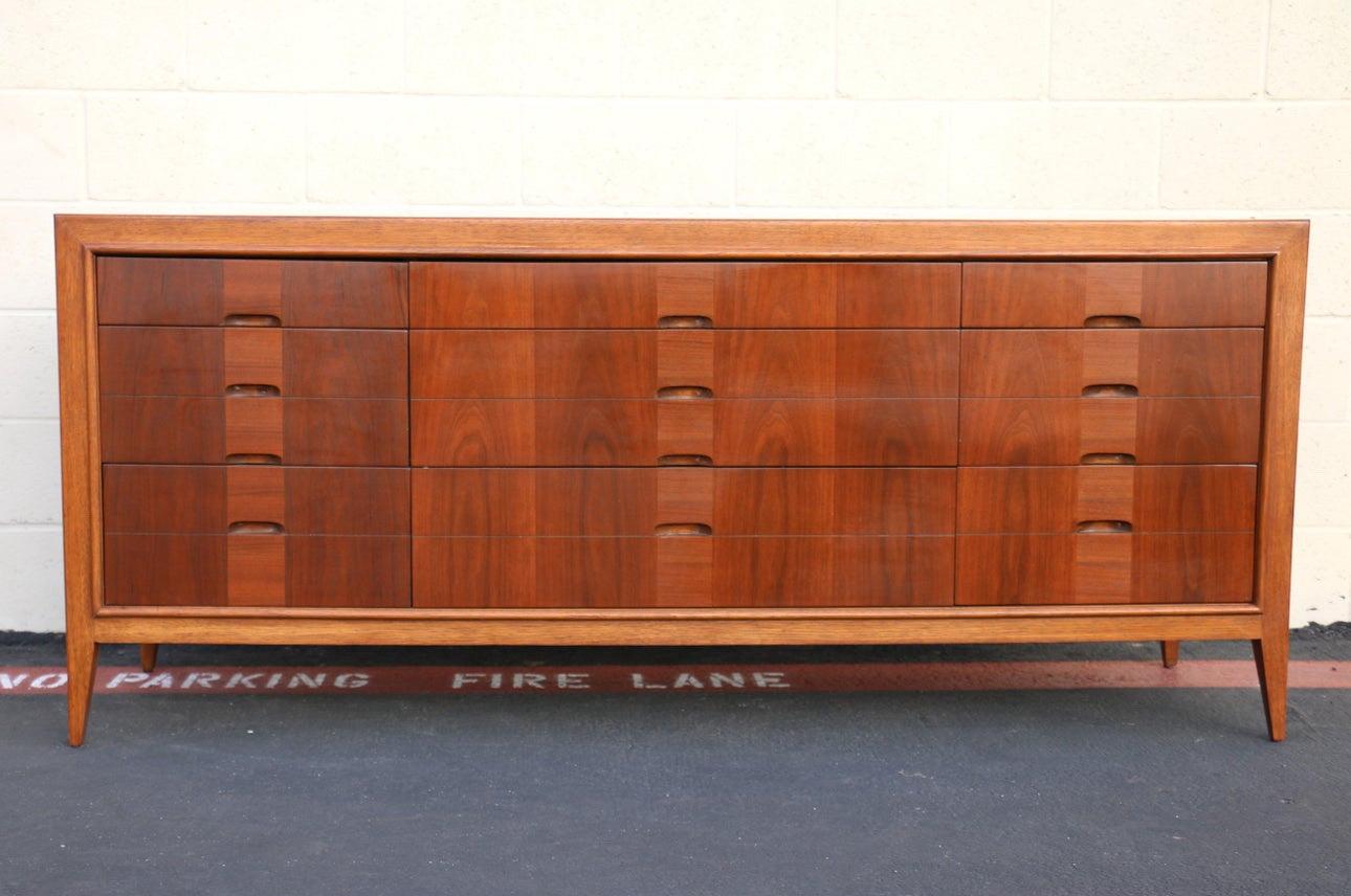 Mid-Century Modern dresser made of walnut and oak wood. It looks like has 12 drawers but it is a nine drawer dresser. Just a really cool detail. Also, the combination of two different kinds of wood brings to the dresser a spectacular contrast and