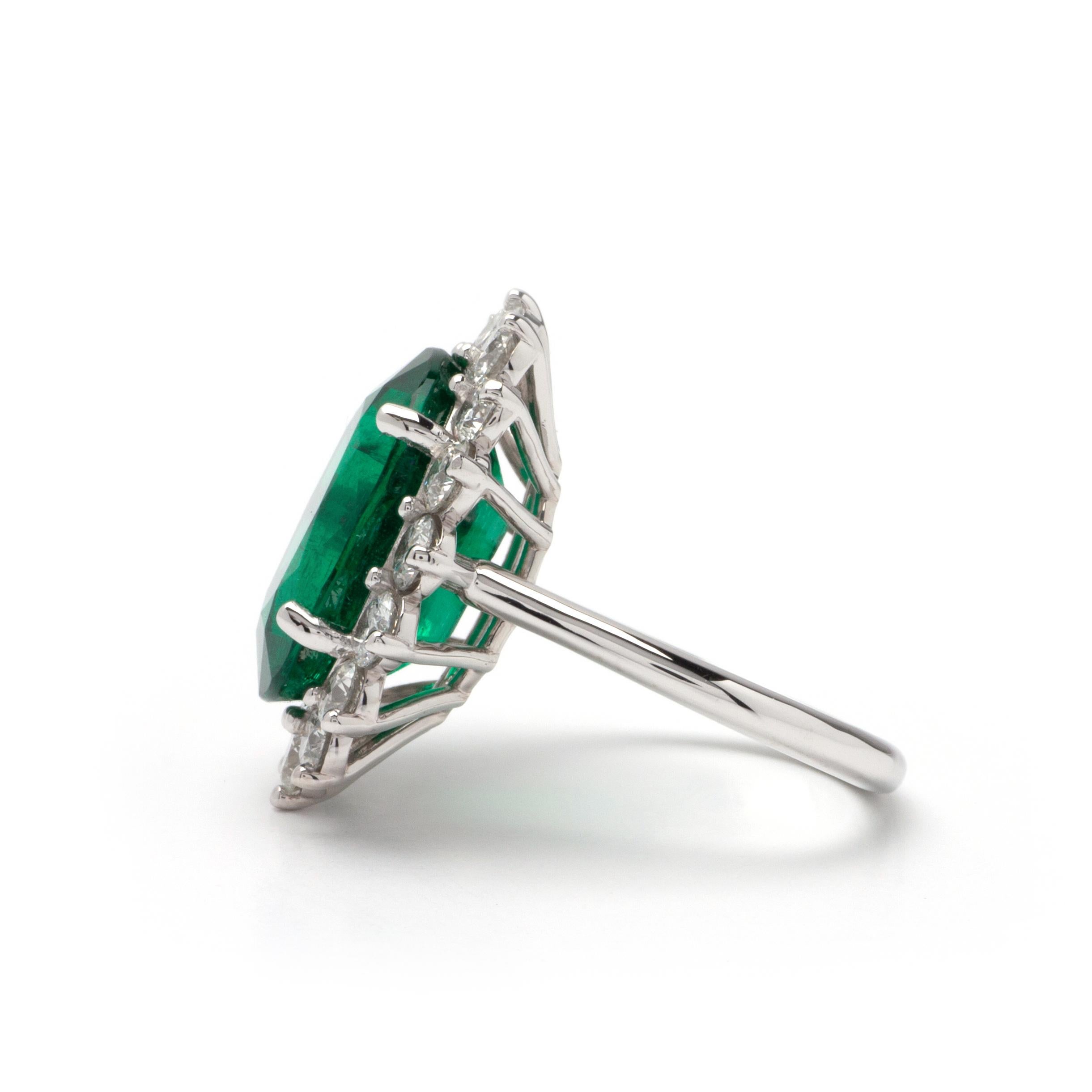 This ring features a halo design of F color, SI1 clarity, and 2.40ct Round side diamonds set in 14K white gold. The center gemstone is a 10.64ct Oval green emerald measuring 16.86 x 13.01 x 7.92mm. Finger size 7