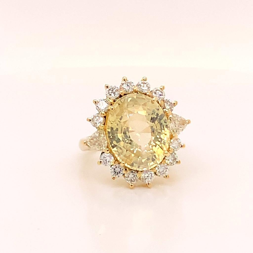 This glitteringly glamorous beauty is made of a stunning 10.68 Carat Oval Cut Unheated Yellow Sapphire surrounded by a halo of glimmering diamonds weighing 1.66 Carats in total set in 18K Yellow Gold. This ring has a unique twist, with the halo of
