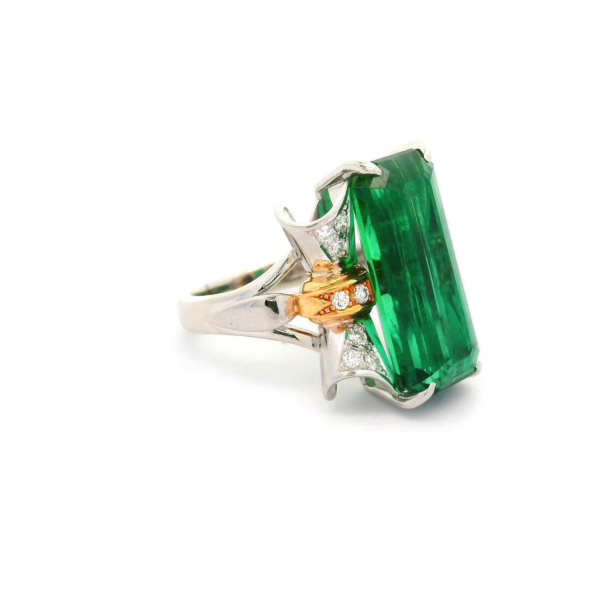 A striking green tourmaline, weighing 10.69 carats, is the centerpiece of this contemporary ring. The baguette-cut stone is complemented by round-cut white diamonds, totaling 0.22 carats, adding a delicate sparkle. Crafted with a blend of 18k gold,