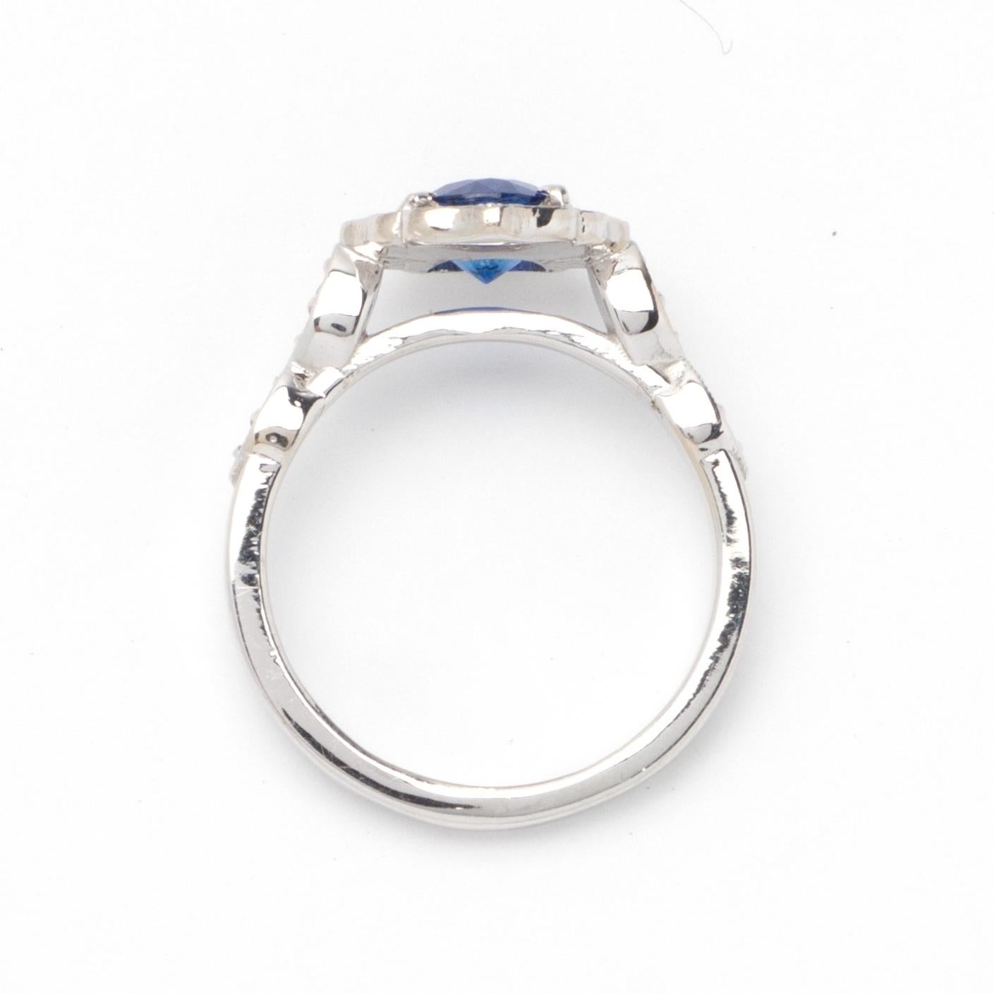 This ring features a halo design of G color, VS1 clarity, and .25ct round side diamonds set in 14K white gold. The center gemstone is a 1.06ct round blue sapphire. 