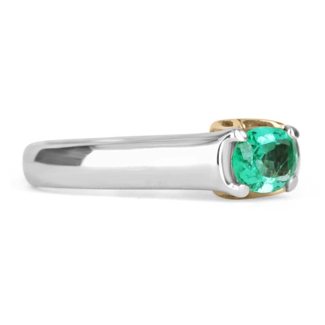 Displayed is a classic Colombian emerald solitaire oval-cut engagement ring in platinum & 18K gold. This gorgeous solitaire ring carries a full 1.06-carat emerald in a four-prong, East to West setting. Fully faceted, this gemstone showcases