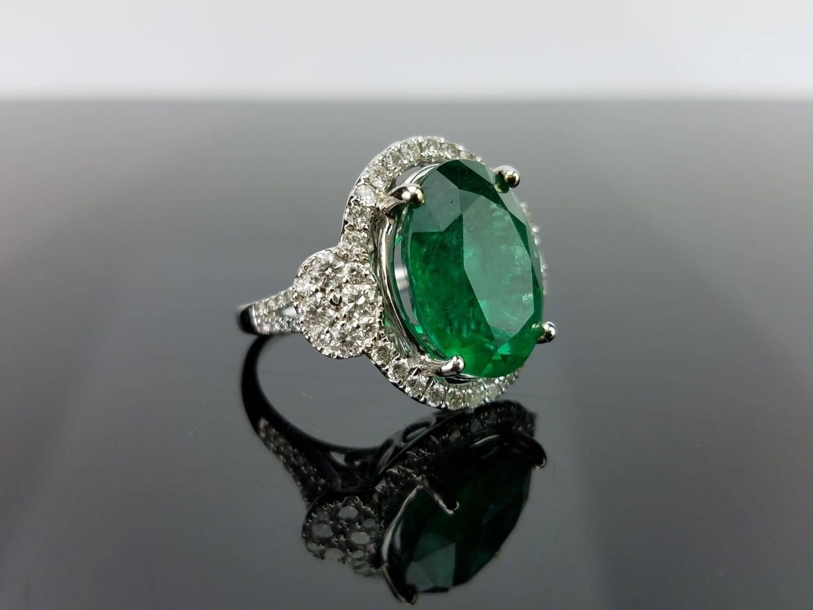 An art-deco looking, statement 10.72 carat oval shaped Zambian Emerald cocktail ring, set with white Diamonds in 18k white Gold.

Stone Details: 
Stone: Zambian Emerald
Carat Weight: 10.72Carats

Diamond Details: 
Total Carat Weight: 1.8