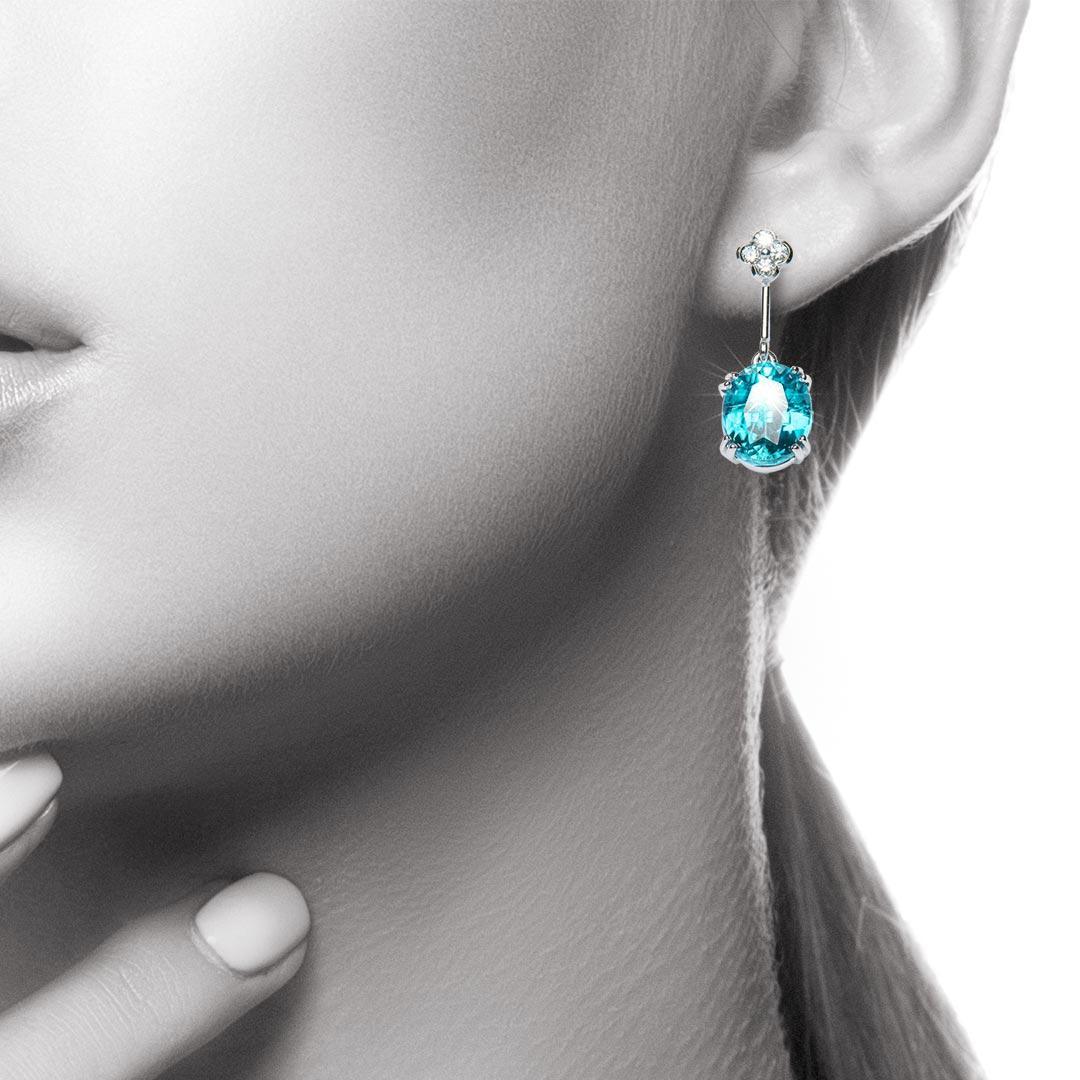 The spectacular blue colour of perfectly cut oval Zircons is offset by fine flower-like diamond cluster tops. A very classical pair of drop earrings with a rare and unusual coloured gemstone. The Zircons weigh a total of 10.72 carats and the total