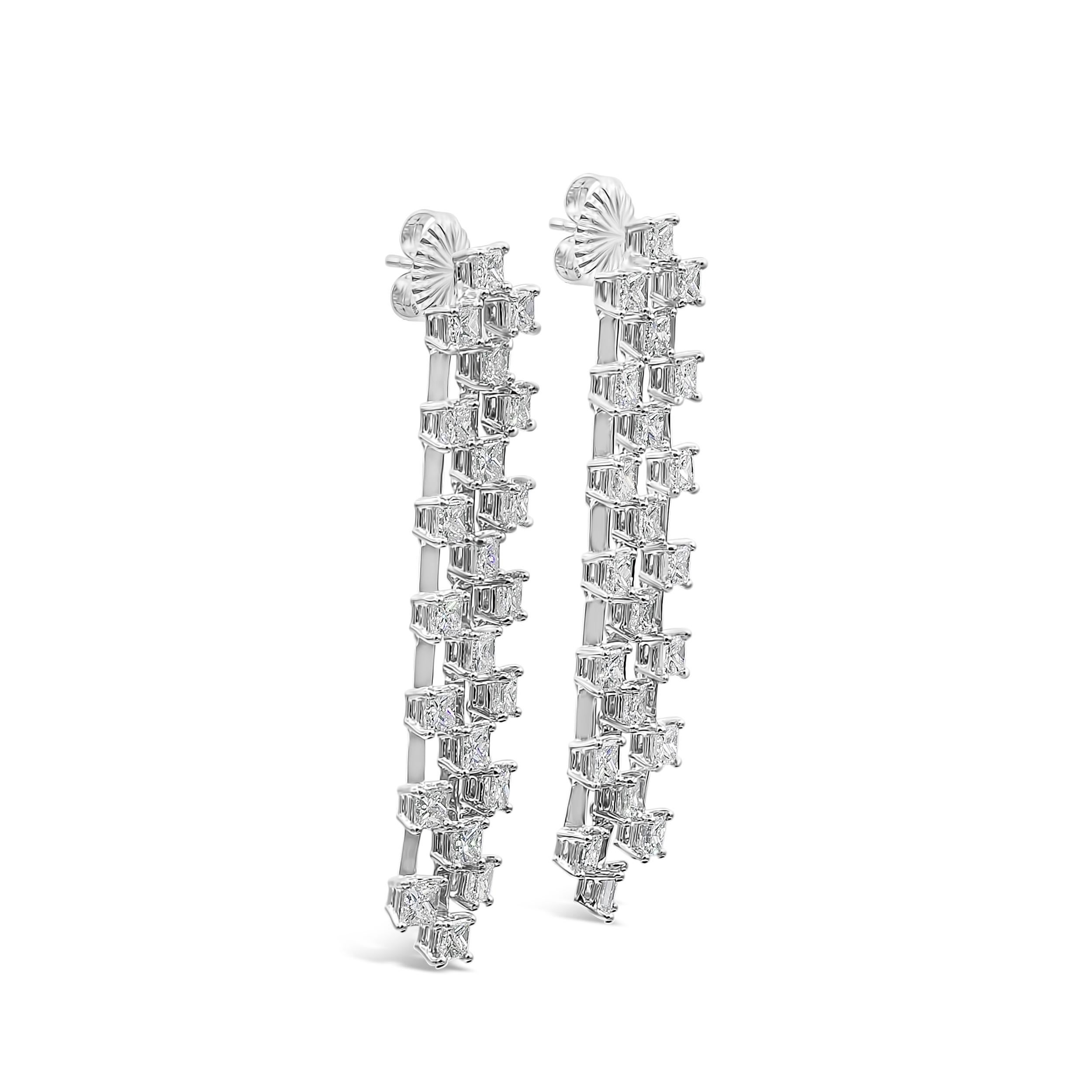 An upscale and dressy pair of waterfall drop earrings showcasing three rows of princess cut diamonds weighing 10.79 carats total, F-G color and VS-SI in clarity. Each set in its own  four prong basket setting and Finely made in 18K White Gold. 2.38
