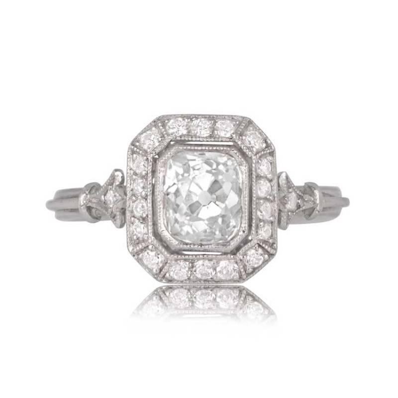 This ring centers on a rare antique cushion cut diamond that has been mounted into a stunning handcrafted platinum mounting. The center diamond weighs approximately 1.07 carats, J color, and VS2 clarity. A halo of diamonds surrounds the bezel-set