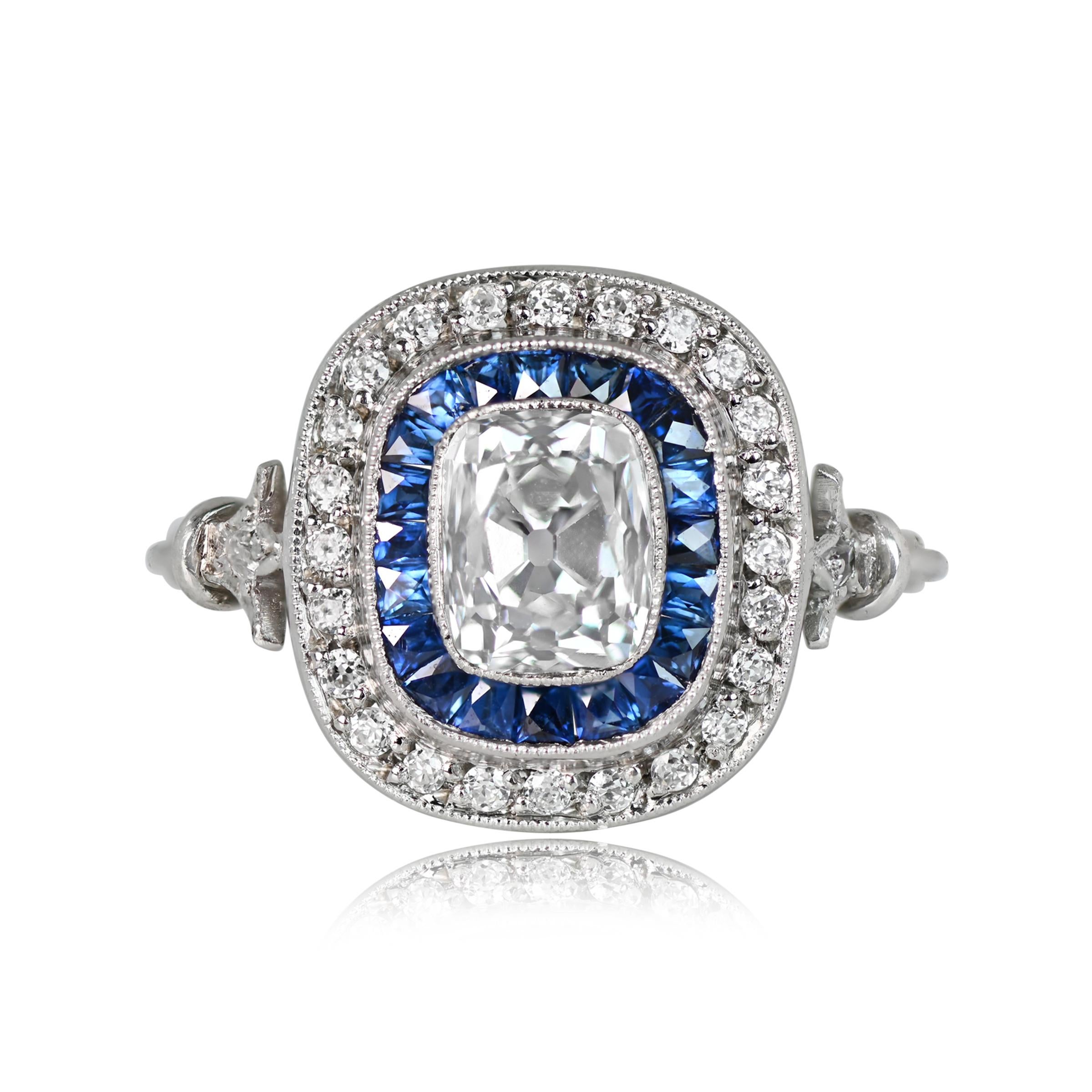 An exquisite hand-crafted platinum engagement ring features an elongated antique cushion cut diamond, approximately 1.07 carats. A double row of natural blue French cut sapphires and old European cut diamonds gracefully encircle the center stone.