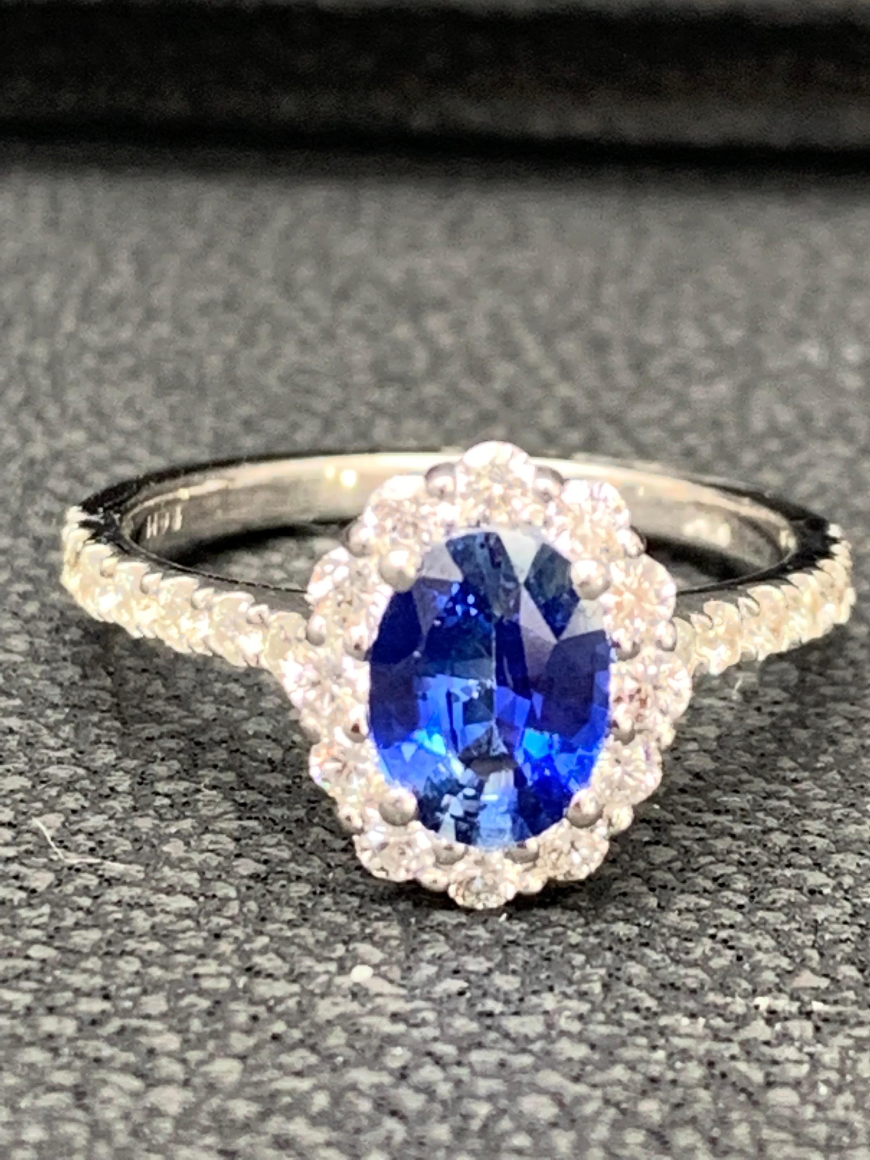 Showcases a oval cut blue sapphire weighing 1.08 carats, surrounded by a single row of 26 round brilliant diamonds in a seamless halo design. Set in a thin 14 karat white gold band accented with diamonds. Diamonds weigh 0.93 carats total.

Style