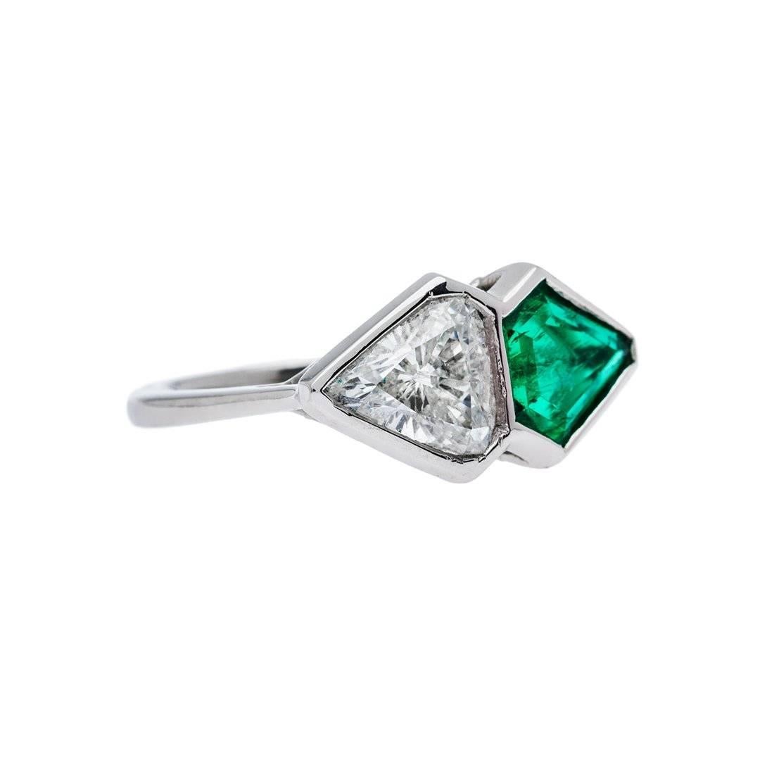 Old materials combined with new design ingeniously realized to create this singular ring. Featuring a mixed shield cut diamond that is H-I color, SI2 clarity perfectly paired with a 0.84 carat forest green shield cut emerald. Hand crafted in