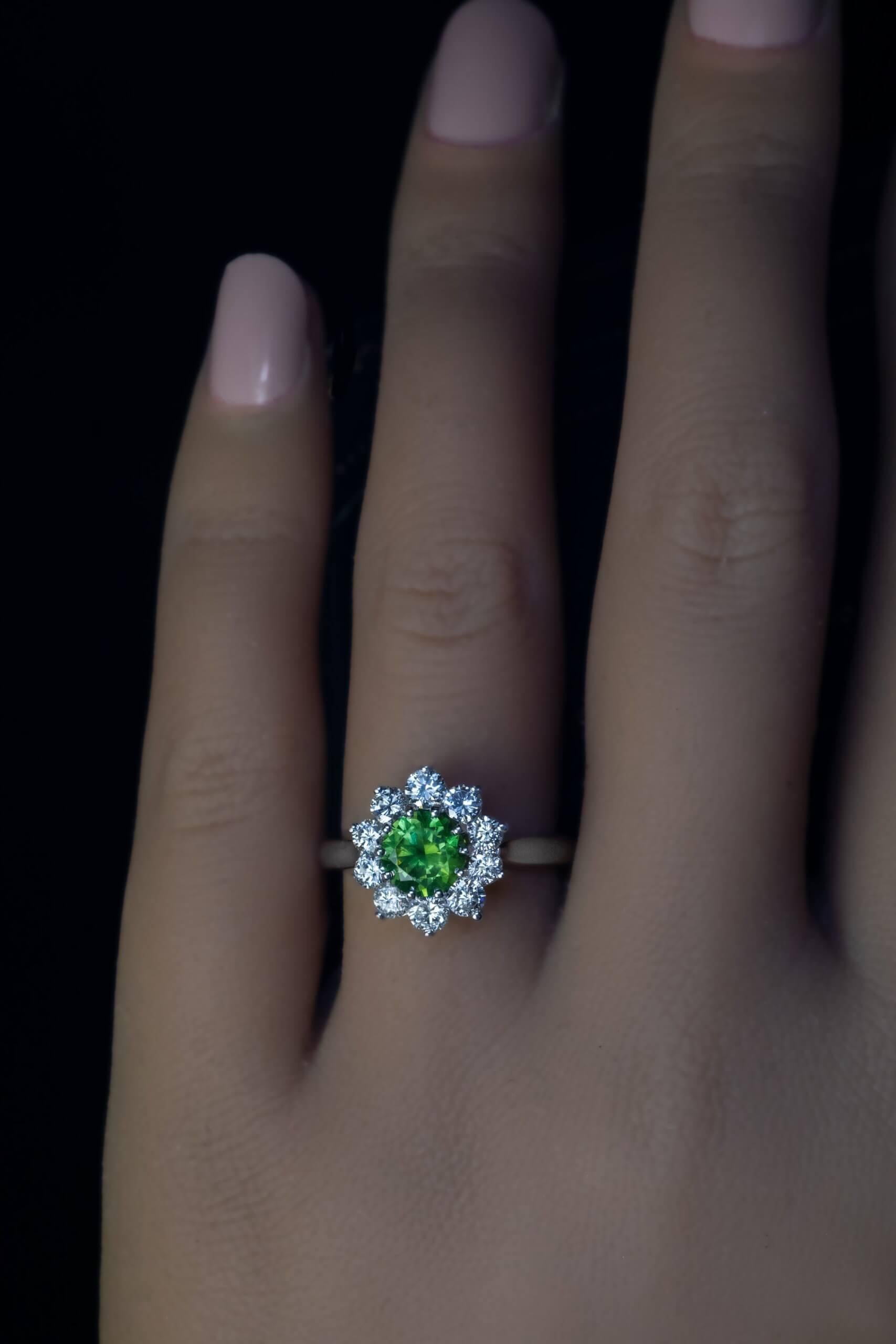 This contemporary custom-made cluster ring is crafted in 14K white gold. The ring features a golden green 1.08 ct brilliant cut Russian demantoid from the Ural Mountains. The demantoid is surrounded by bright white diamonds (F-G color, VS-SI