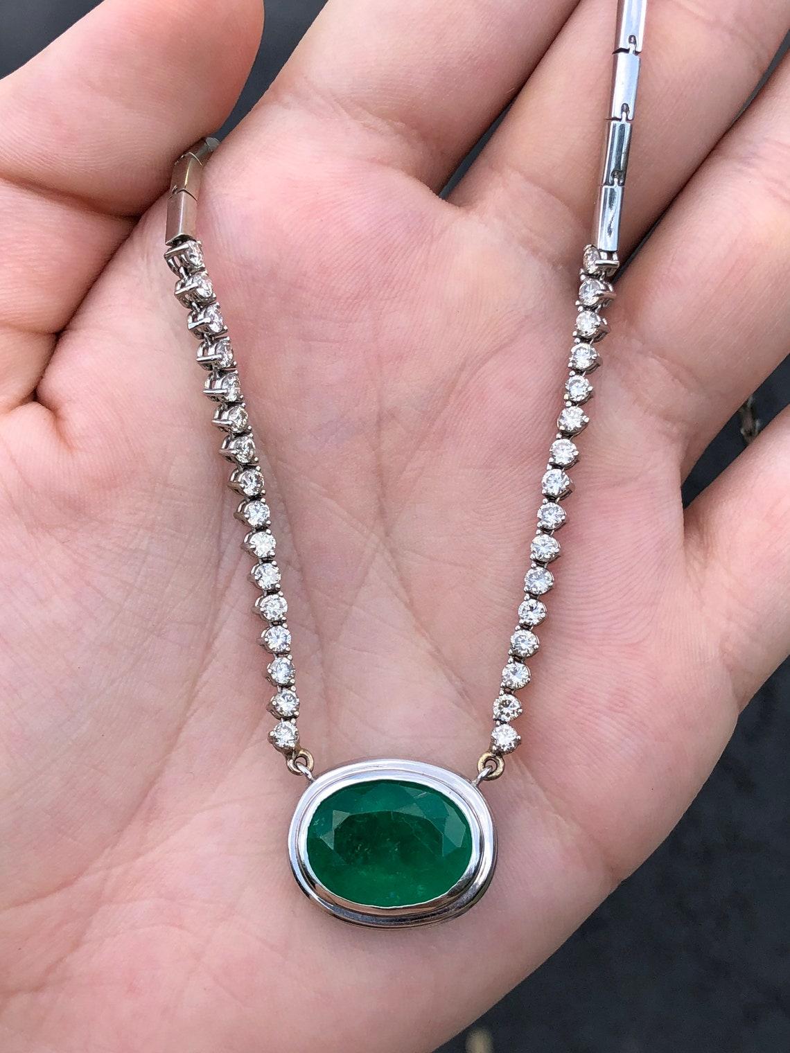 This necklace is not for the faint of heart! Featured here is a stunning oval Colombian emerald and diamond necklace made in fine 14K white gold. Displayed is a rich, dark green oval emerald with very good eye clarity for its huge 9.09-carat size.