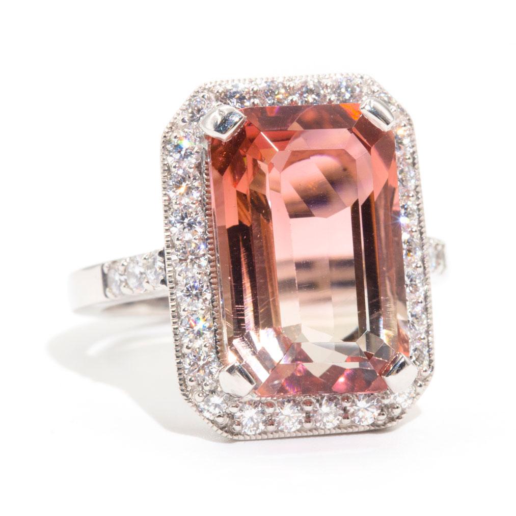 Forged in platinum is this vintage inspired halo ring featuring a striking 10.84 carat emerald cut natural bi coloured tourmaline complimented by a total of 1.20 carats of sparkling round brilliant cut diamonds. We have named this breathtaking ring
