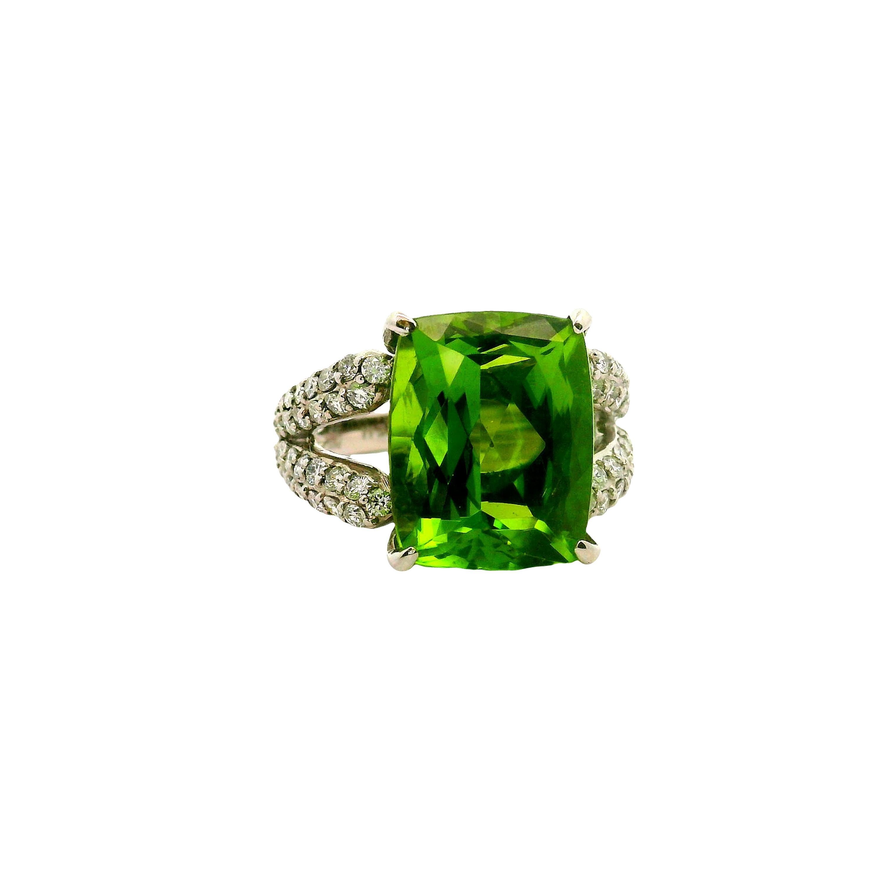 Un llamativo peridoto de 10,89 quilates acapara la atención en este anillo de platino. Presenta un peridoto talla cojín con un vibrante tono verde. Acentuando el peridoto hay diamantes de talla redonda, con un total de 0,94 quilates, que