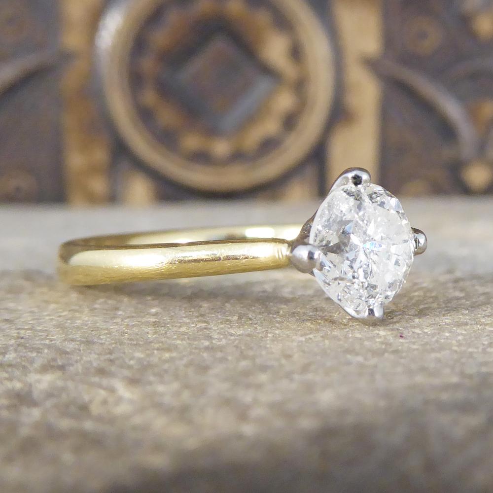 This ring features a round brilliant cut Diamond weighing 1.08ct, four claw set to a white lily-style setting to tapering yellow shoulders in an 18ct Yellow Gold plain polished band. Hallmarked with Birmingham 18ct Gold and Platinum, this beautiful