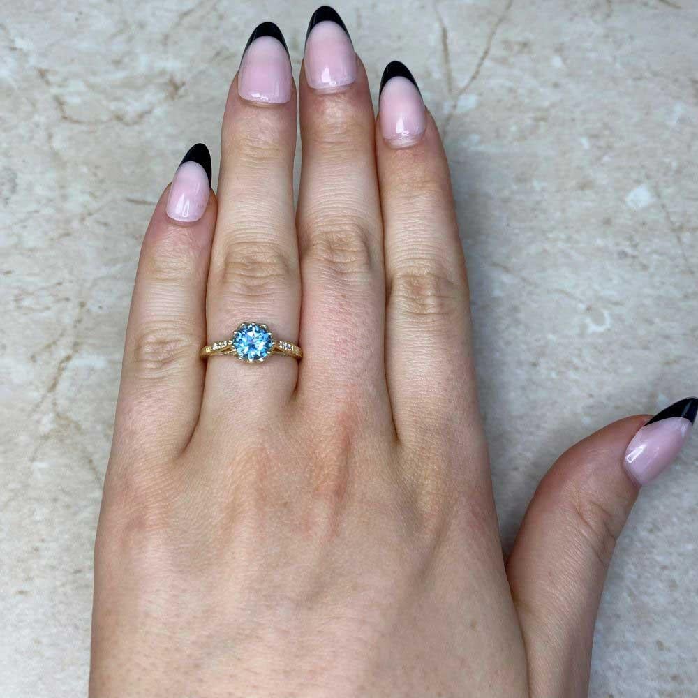 Exuding timeless elegance, this crown-style ring showcases a round-cut natural aquamarine weighing approximately 1.00-carats. Its captivating teal hue radiates brilliance, beautifully complemented by a handcrafted 18k yellow gold setting. The design