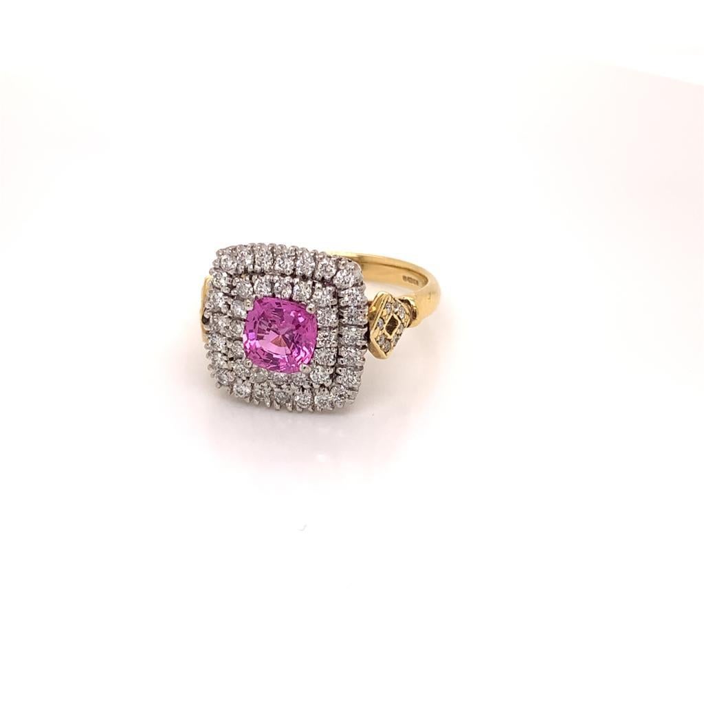 This Masterpiece is a Unique 18K White and Yellow Gold Ring featuring a Dazzling Cushion cut Pink Sapphire weighing approximately 1.09 carats at its centre. This Precious stone is surrounded by two rows of Round Brilliant Diamonds with Diamonds also