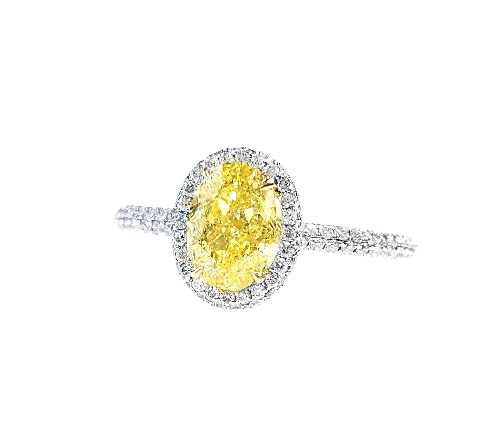 Bague de fiançailles ornée d'un diamant de taille ovale de 1,09 carat, certifié par le GIA comme étant un diamant de couleur naturelle jaune intense et de pureté VS1. Ce modèle classique met en valeur la beauté de la pierre centrale grâce à un halo