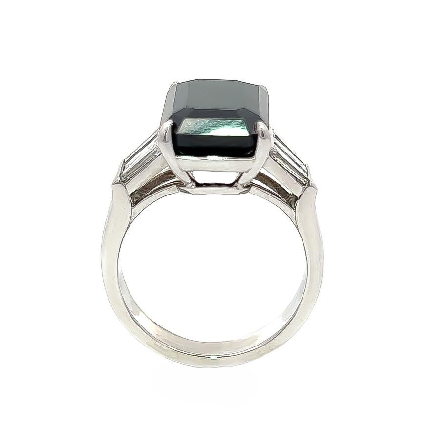 Wir präsentieren unseren bezaubernden Ring mit einem prächtigen schwarzen Diamanten im Kissenschliff mit einem Gewicht von 9,90 Karat. Strahlende Baguette-Diamanten schmücken beide Seiten, insgesamt 1,10 ct mit G-H Farbe und VS Reinheit. Dieser