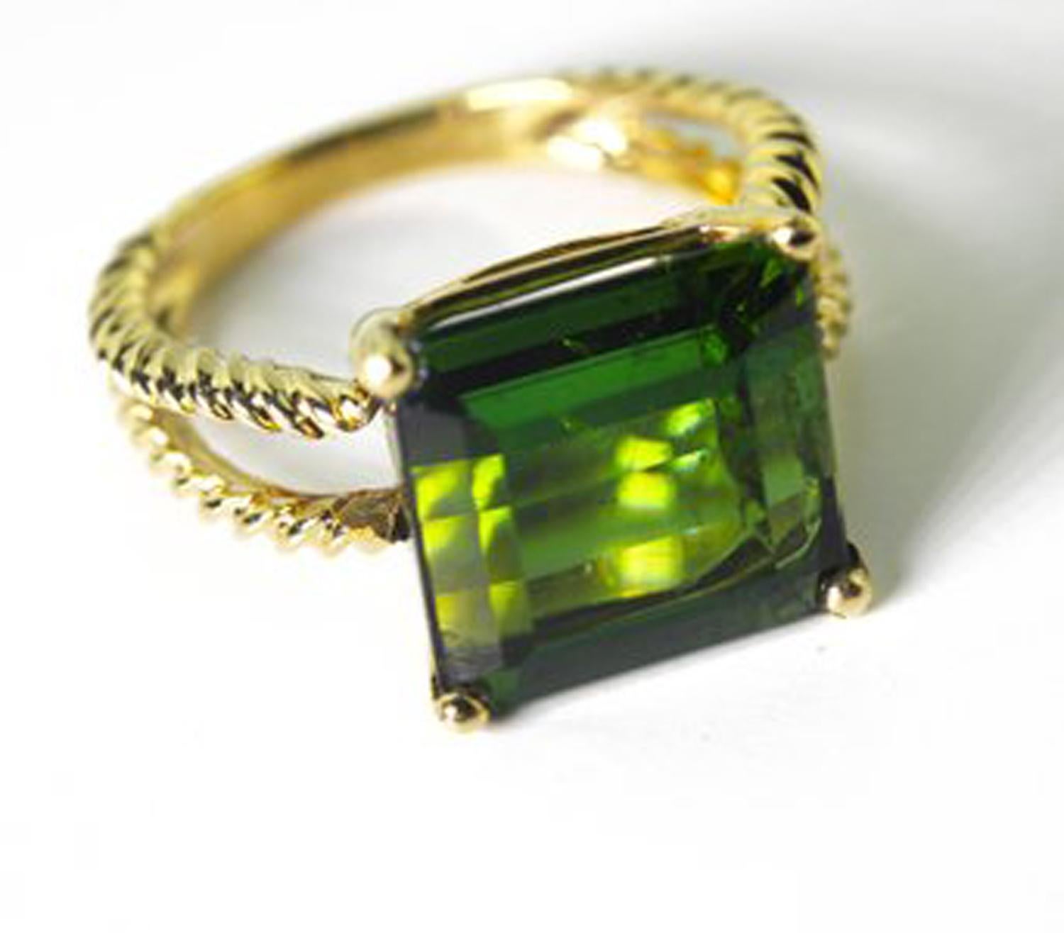 Beautiful emerald cut glittering green 10.96 Carat Tourmaline set in a 14 KT yellow gold ring size 7.5 (sizable for free).  The gemstone measures approximately 12 mm x 11 mm.  There are no eye visible inclusions in the gemstone.  