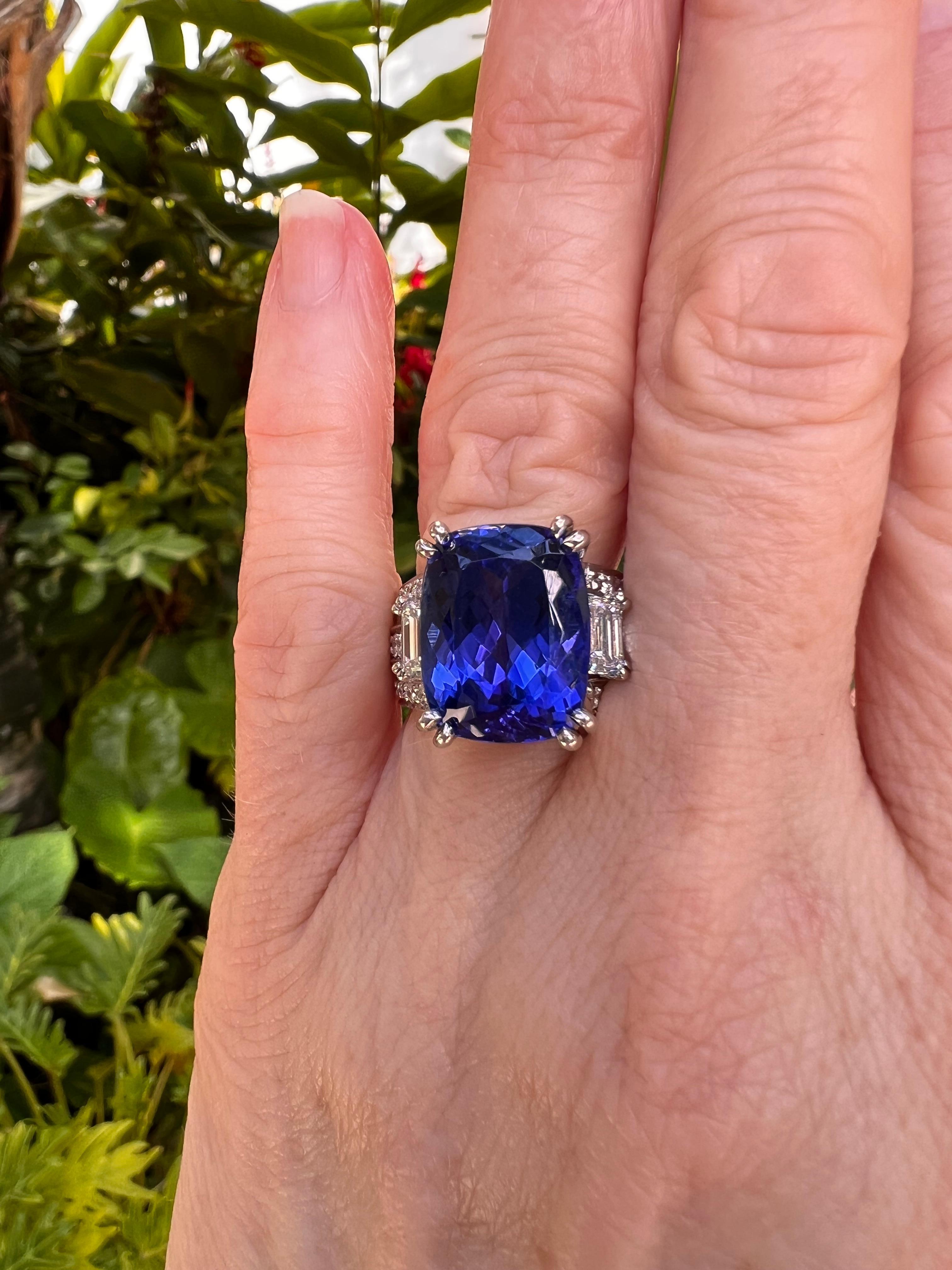 Platinum custom designed ring by Coffin & Trout, centering a cushion-cut tanzanite weighing 10.99 carats with a vibrant bluish-violet color and held by four double prongs.  Flanked by two emerald-cut diamonds on the sides totaling 1.00 total carats.