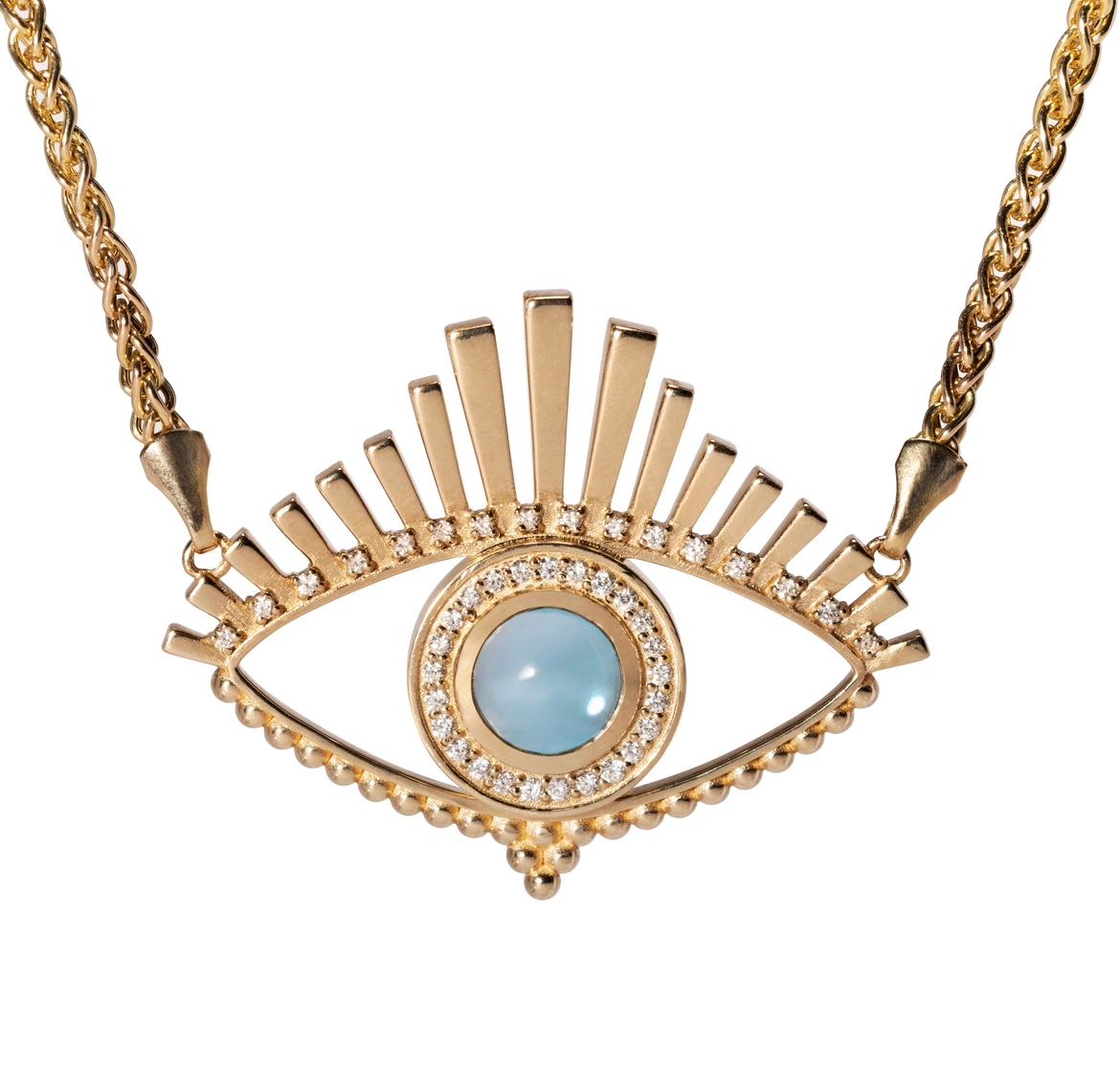 This exquisite design of gold and gems radiates protection and talismanic appeal, with a central blue topaz encircled by natural diamonds, upper diamond-bordered lashes, and a lower line of gold beading. As a timeless symbol of deflecting the 