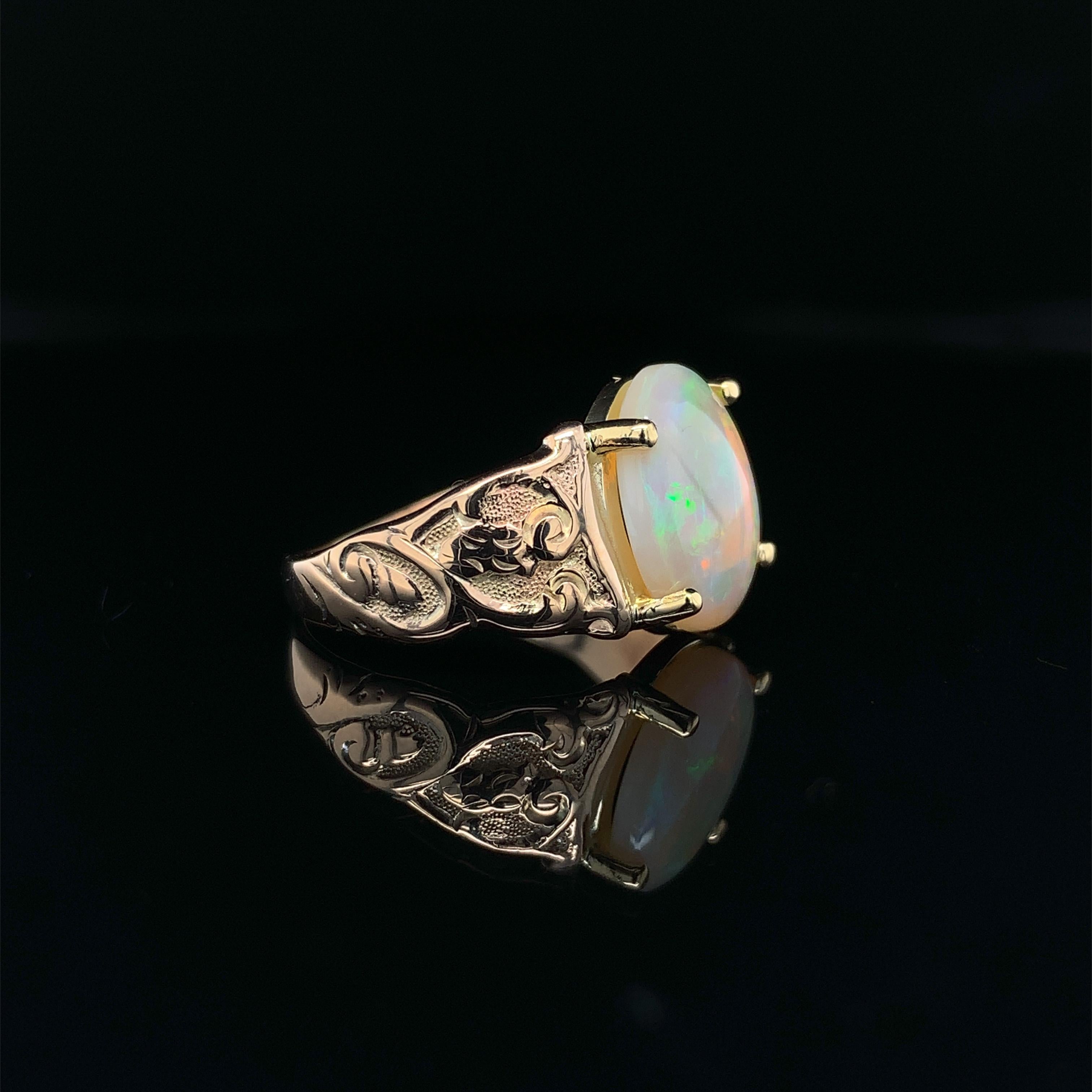 Vintage 10K yellow gold 1.98 carat opal ring with a new 14K yellow gold head. The genuine natural Australian opal measures about 11mm x 9mm. The opal is translucent and has very lively play of color with all colors. The ring has hand engraving on