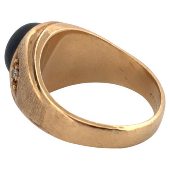 Questo sorprendente anello vintage è realizzato in oro giallo spazzolato 10k, con una finitura calda e strutturata che ne esalta il design audace. Al centro, un affascinante zaffiro ovale cabochon a stella si mette in evidenza, mostrando il suo