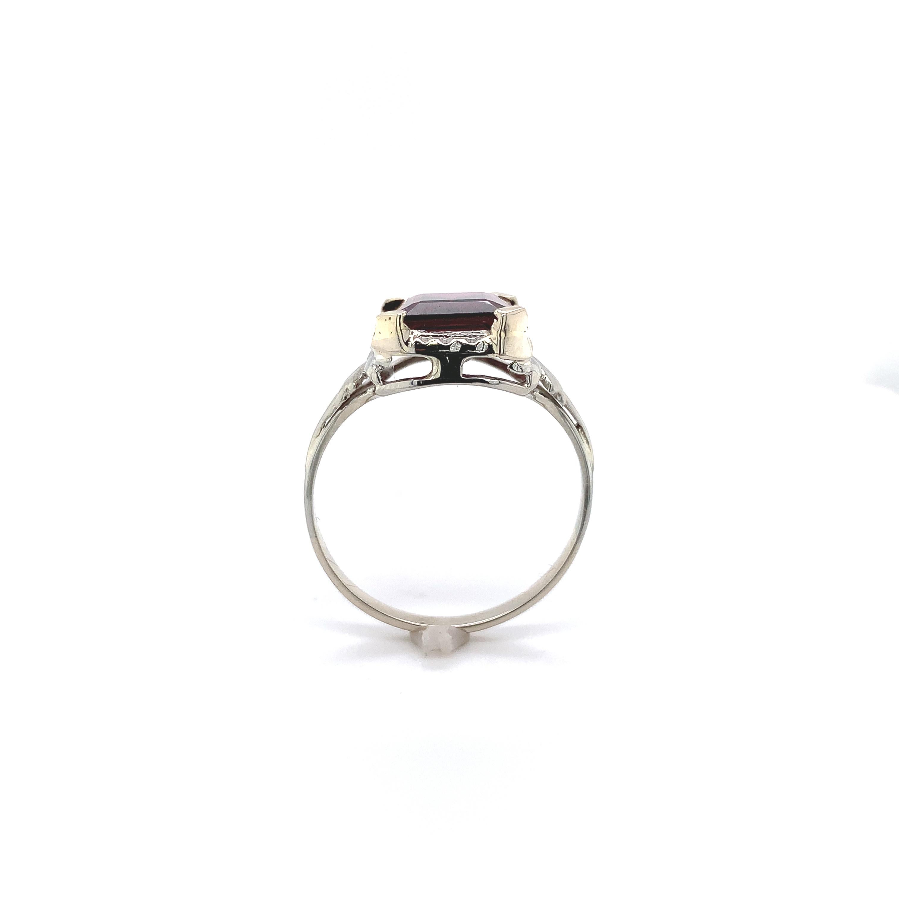 14K white gold ring set with an emerald cut rhodolite garnet weighing 3.90 carats. The very pretty raspberry colored garnet measures about 10mm x 8mm and has 4 new prongs. There is a border of hand engraved design. The ring fits a size 8 1/4 finger,