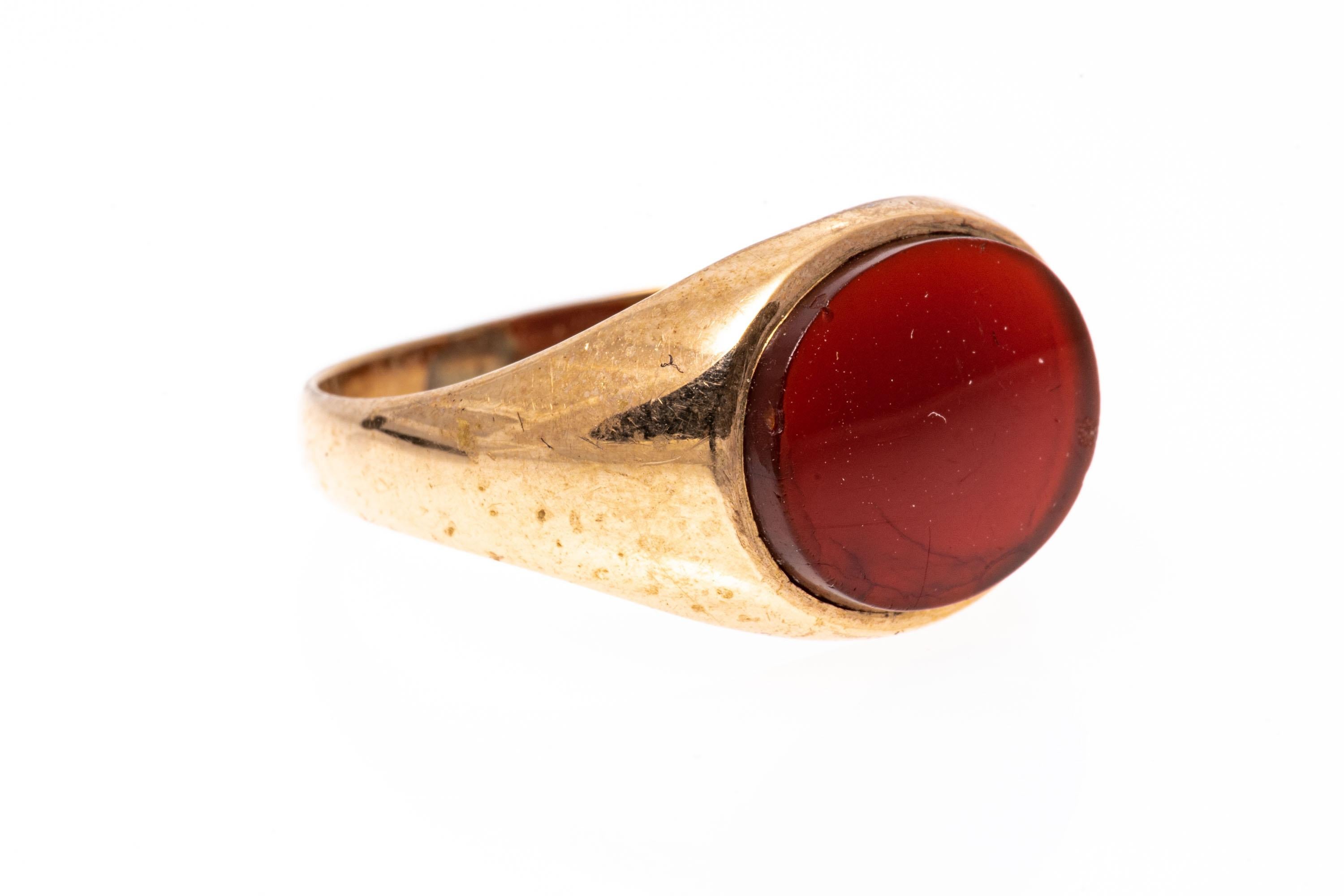 10k gold ring. This attractive signet style ring features a center, horizontal oval carnelian, adorned with wide, simple high polished sides.
Marks: None, tests 10k
Dimensions: 7/16