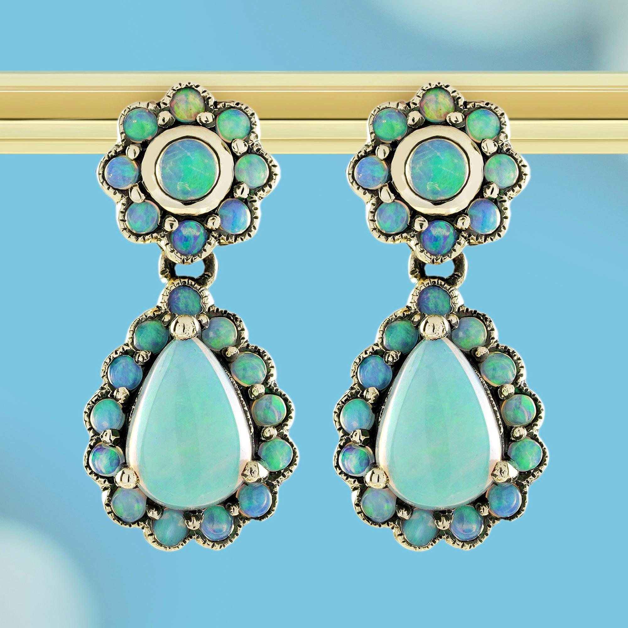 Diese bezaubernden und zeitlosen floralen Tropfenohrringe im Vintage-Stil sind mit leuchtenden Opalsteinen in glatter Zargenfassung besetzt. Jeder Ohrring erblüht wie eine zarte Blume mit Opalen, die in einem Tanz schillernder Farben schimmern. Das