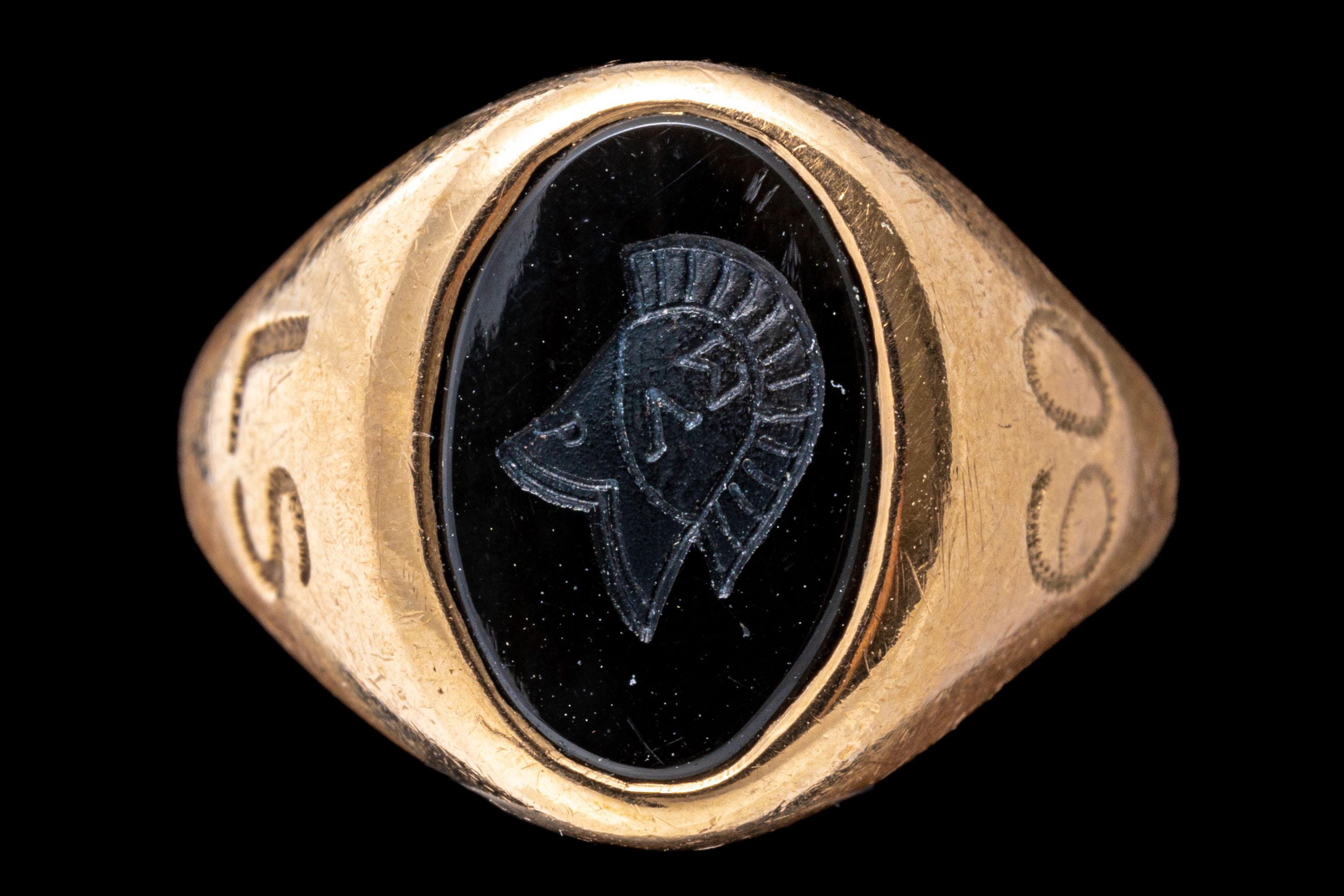 10k gold ring. This handsome vintage signet style class ring features a center, oval black onyx, decorated with an intaglio logo engraving and adorned with wide, simple high polished sides, engraved.
Marks: 10k
Dimensions: 5/16