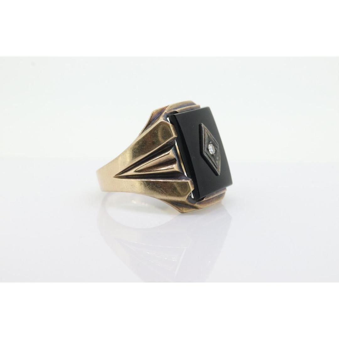 Vintage By aus den 1960er Jahren
Größe: 10 1/2 US
MATERIALIEN: Gold
Edelstein: Onyx
Farbe des Edelsteins: Schwarz

Bandfarbe: Gold

Dies ist ein einzigartiger Ring. Herrenring mit Onyx und Diamant in der Mitte. Dreieckiger Schulterstiel

Größe