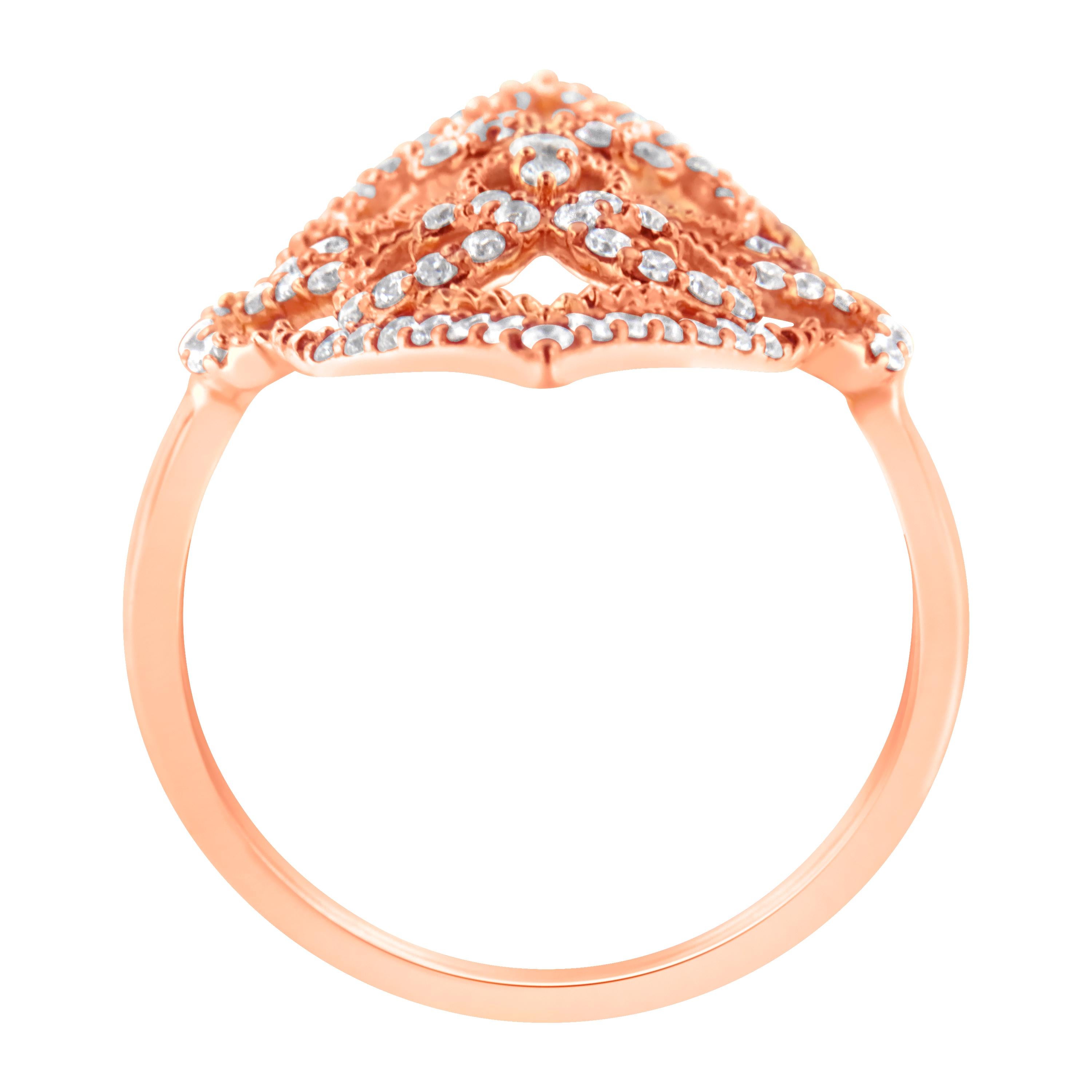 This intricately designed cocktail ring features a central cluster of three round diamonds surrounded in an elaborate scrolled motif accented by further diamonds. Crafted in 10 karat rose gold, it adds a dramatic touch to any outfit. It has a total