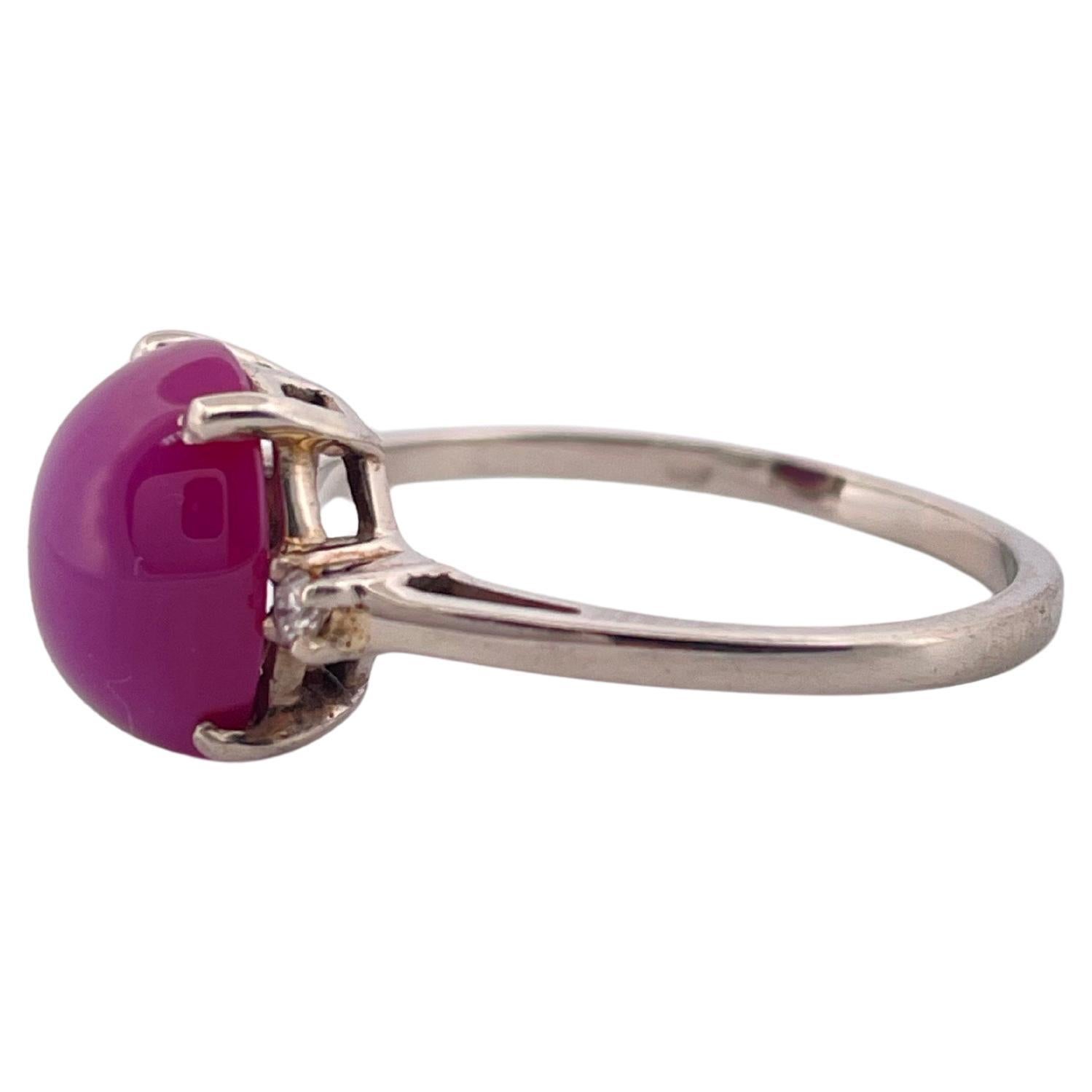 Cette élégante bague en or blanc 10 carats présente un design frappant de 2,6 grammes centré par un captivant rubis étoilé taillé en cabochon. Cette pierre précieuse d'un rouge violacé vif présente un éclat soyeux et un subtil effet d'astérisme