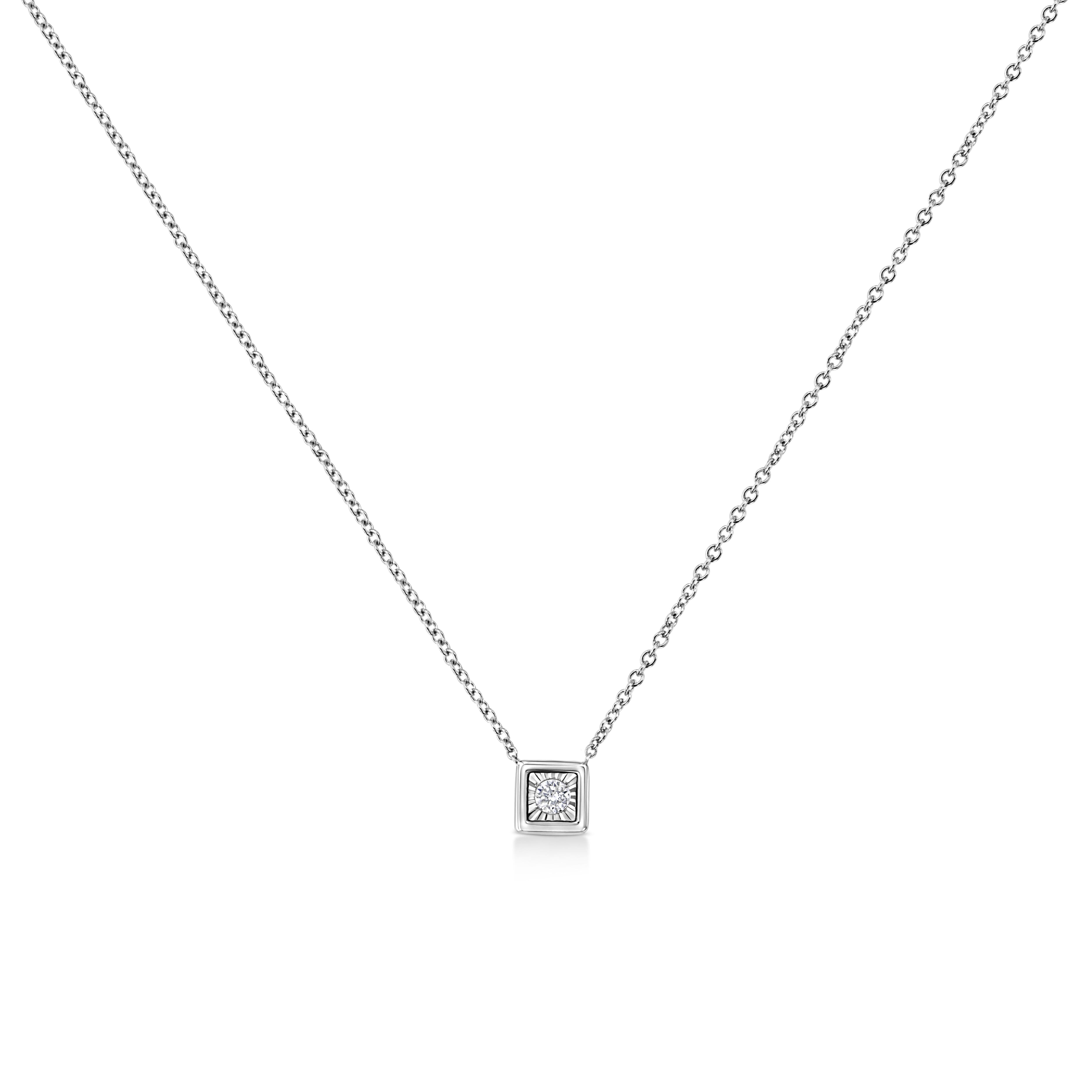 Una collana con pendente di diamanti che presenta un diamante rotondo con taglio a brillante incastonato in un quadrato. Si tratta di una rivisitazione unica di un design classico. Realizzata in oro bianco 10 carati, questa collana ha un peso totale
