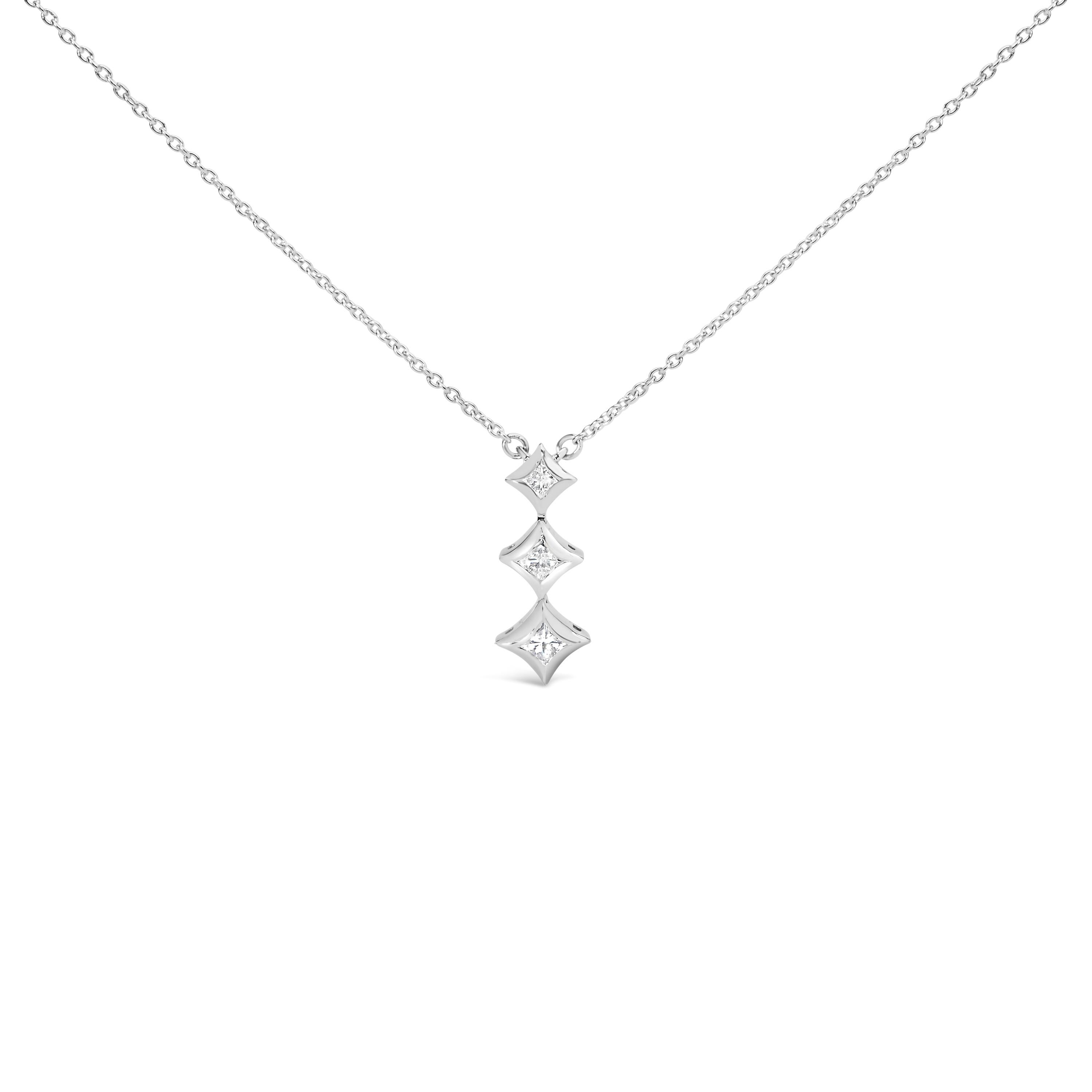 Voici un chef-d'œuvre exquis qui allie sans effort élégance et sophistication. Ce collier pendentif en or blanc 10K met en valeur un trio d'éblouissants diamants de taille princesse, d'un poids total de 1/5 carat. Chaque diamant, méticuleusement