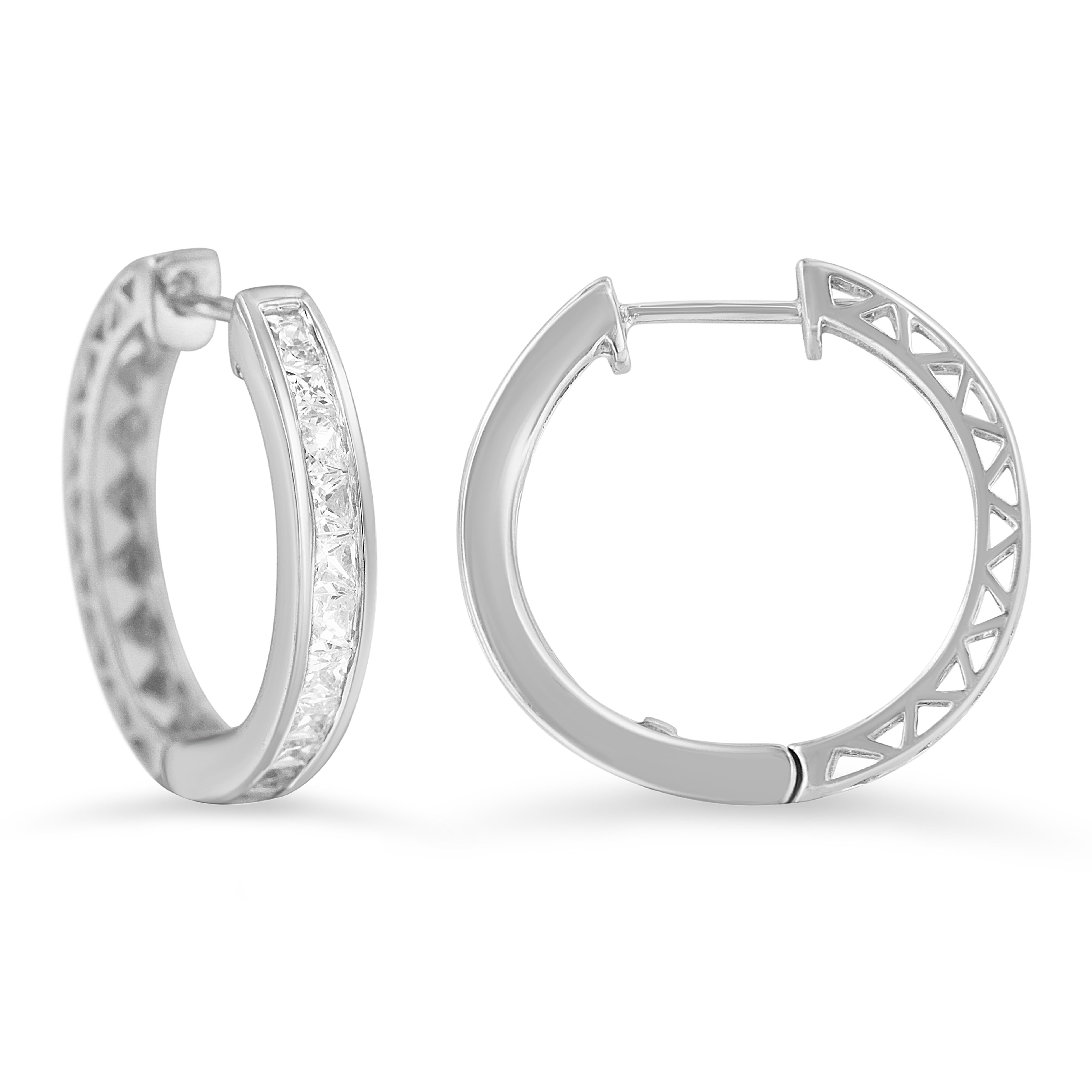 A classic pair of diamond hoop earrings features 18 princess cut diamonds channel-set into 10kt white gold hoops. They have a total diamond weight of 1 carat. These diamonds are color rated as I-J Color, and clarity graded as I2-I3 Clarity. Make