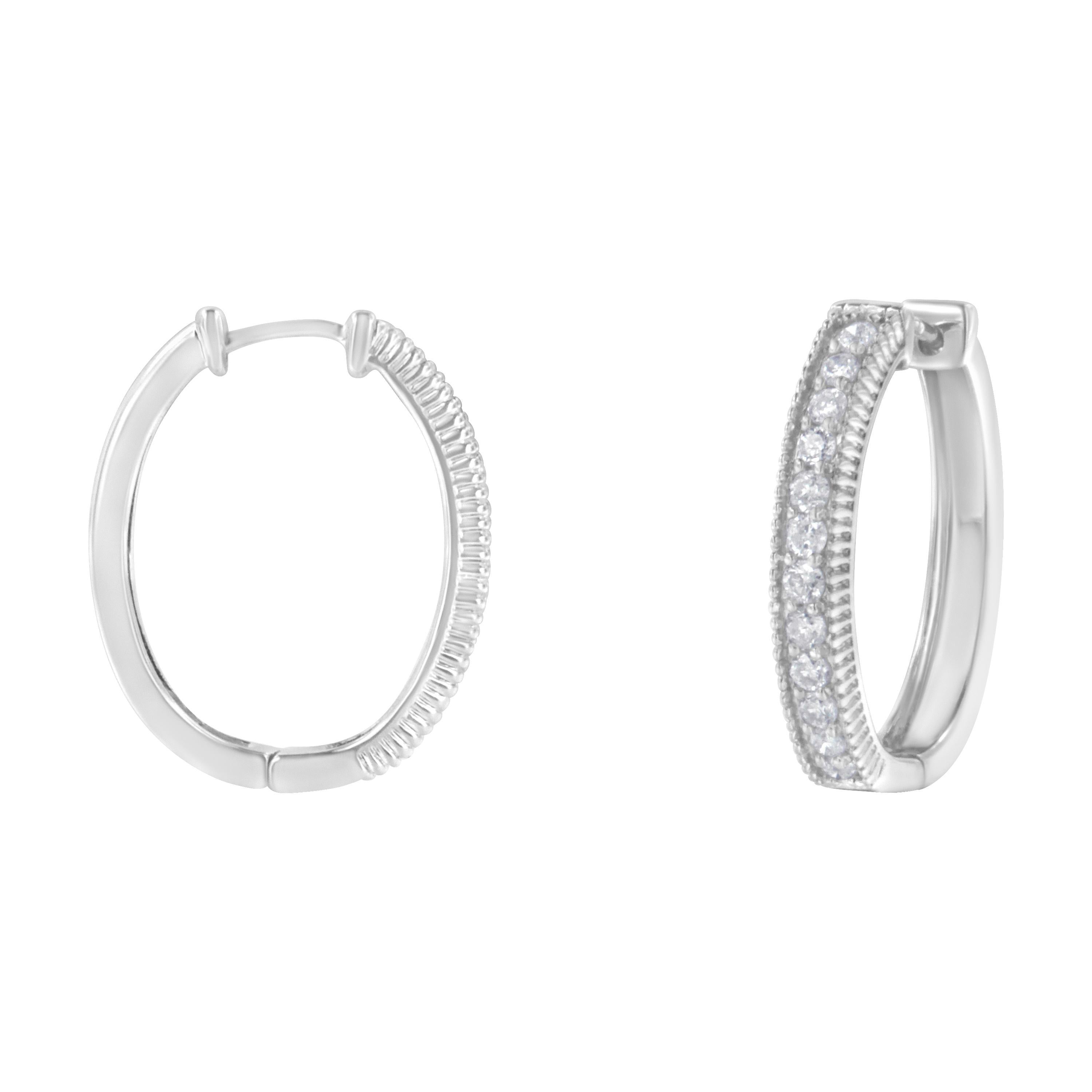 A pair of modern diamond hoop earrings that feature a row of round diamonds. Crafted in 10 karat white gold, they have a total diamond weight of 1 carat. These natural diamonds are color rated as H-I Color, and clarity graded as I1-I2 Clarity. The