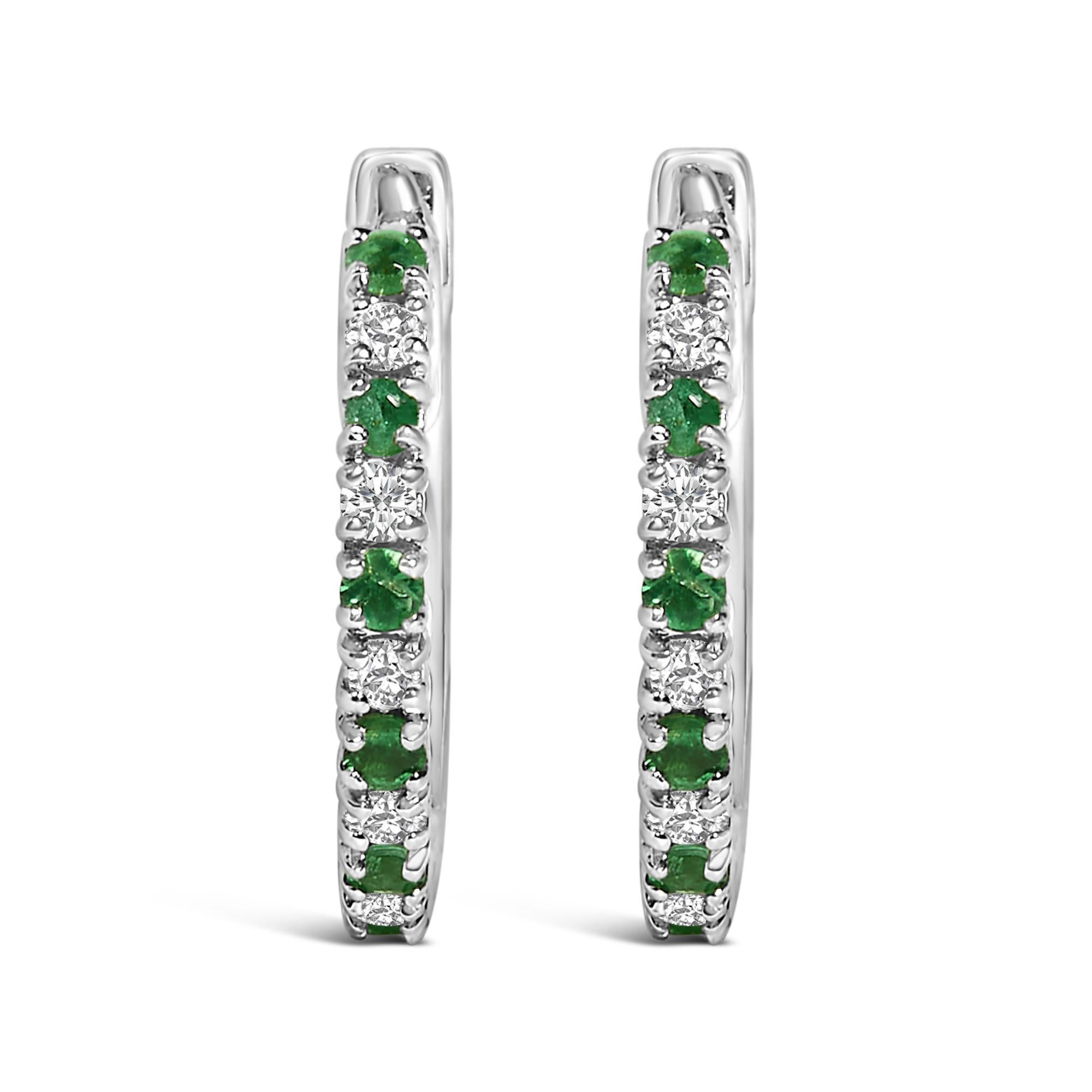 Experimenta la elegancia atemporal de estos pendientes de aro abrazador, elaborados con maestría en oro blanco de 10 quilates rodiado que brilla con un resplandor luminoso. Cada pieza está adornada con una hipnotizante secuencia de esmeraldas