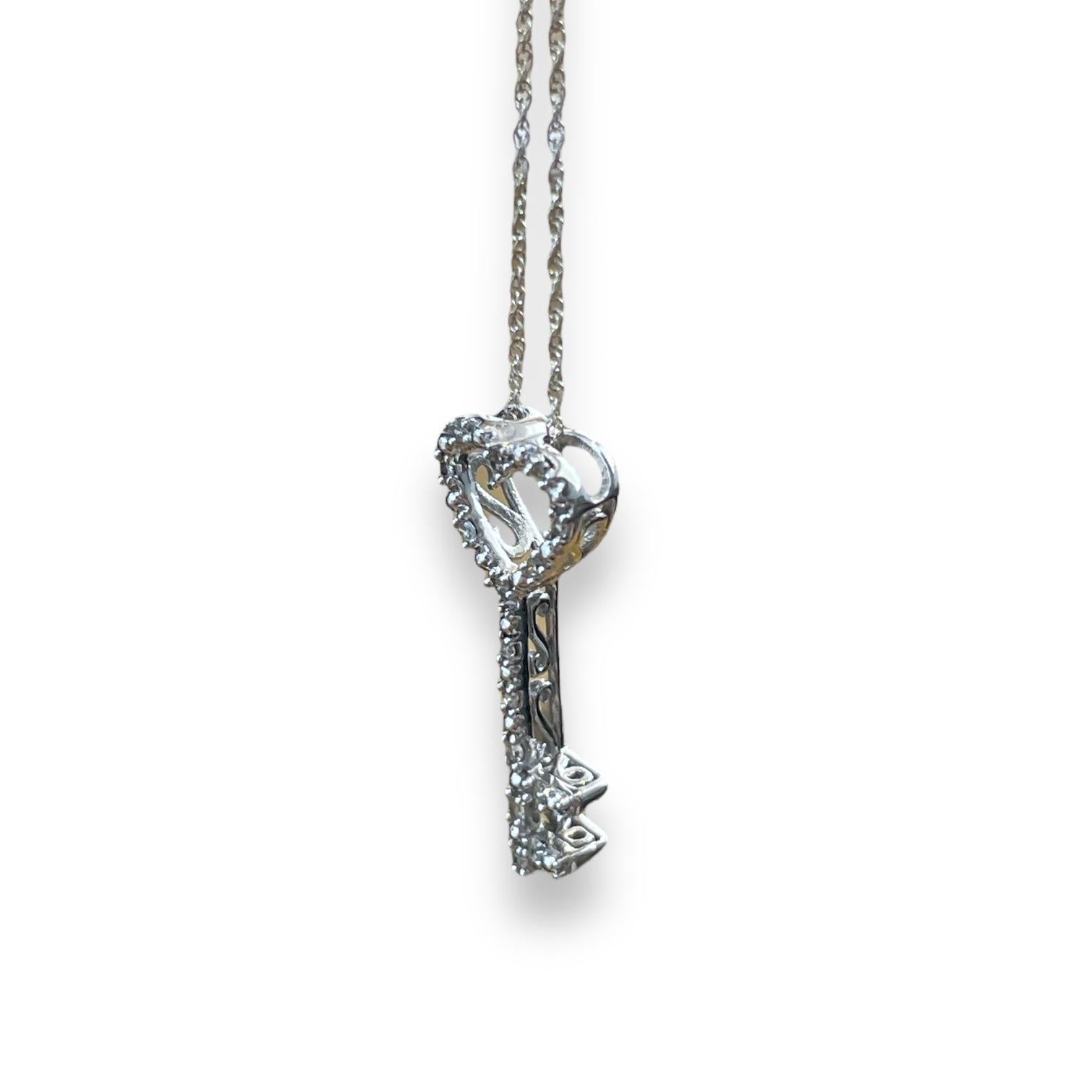 Scopri la bellezza dell'amore e dell'eleganza con questo splendido ciondolo in oro bianco, disegnato a forma di delicata chiave. La parte superiore a forma di cuore è incrostata di diamanti scintillanti, che la rendono un simbolo di passione,
