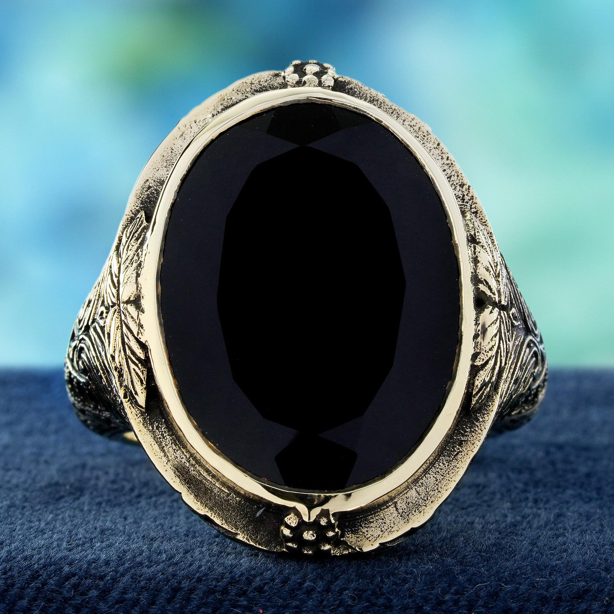 Una profonda e vellutata pietra di onice nera è il punto focale, saldamente incastonata in un elegante castone che ne evidenzia la presenza. Le spalle dell'anello sono ornate da intricati motivi di intaglio, una testimonianza dell'artigianato del